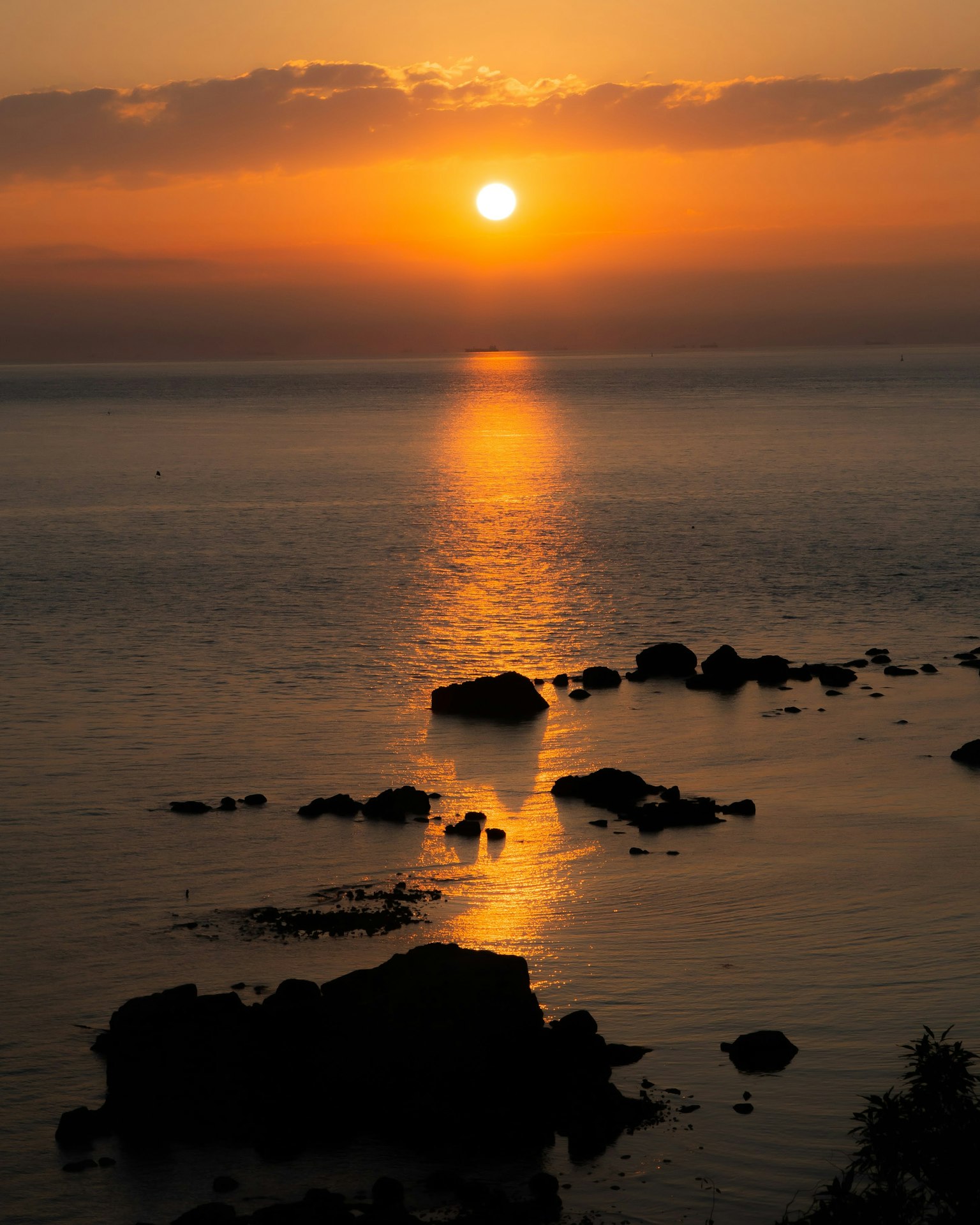 Paysage magnifique d'un coucher de soleil sur la mer rochers et lumière orange se reflétant sur l'eau