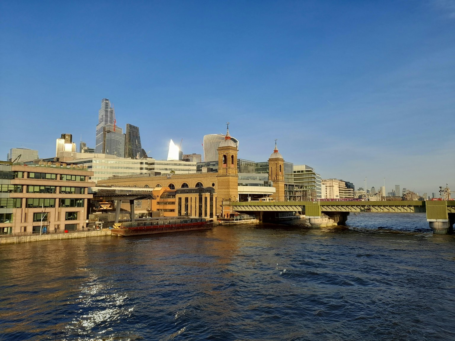A beautiful riverside view showcasing buildings and a bridge against a clear blue sky