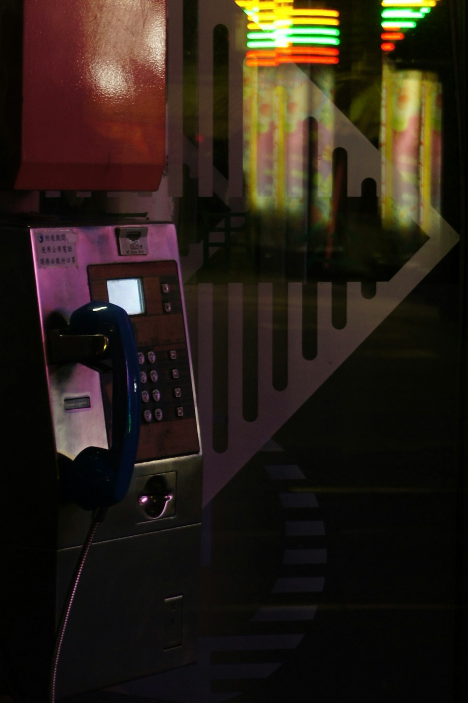 暗い背景にある公衆電話と色とりどりのネオンの光