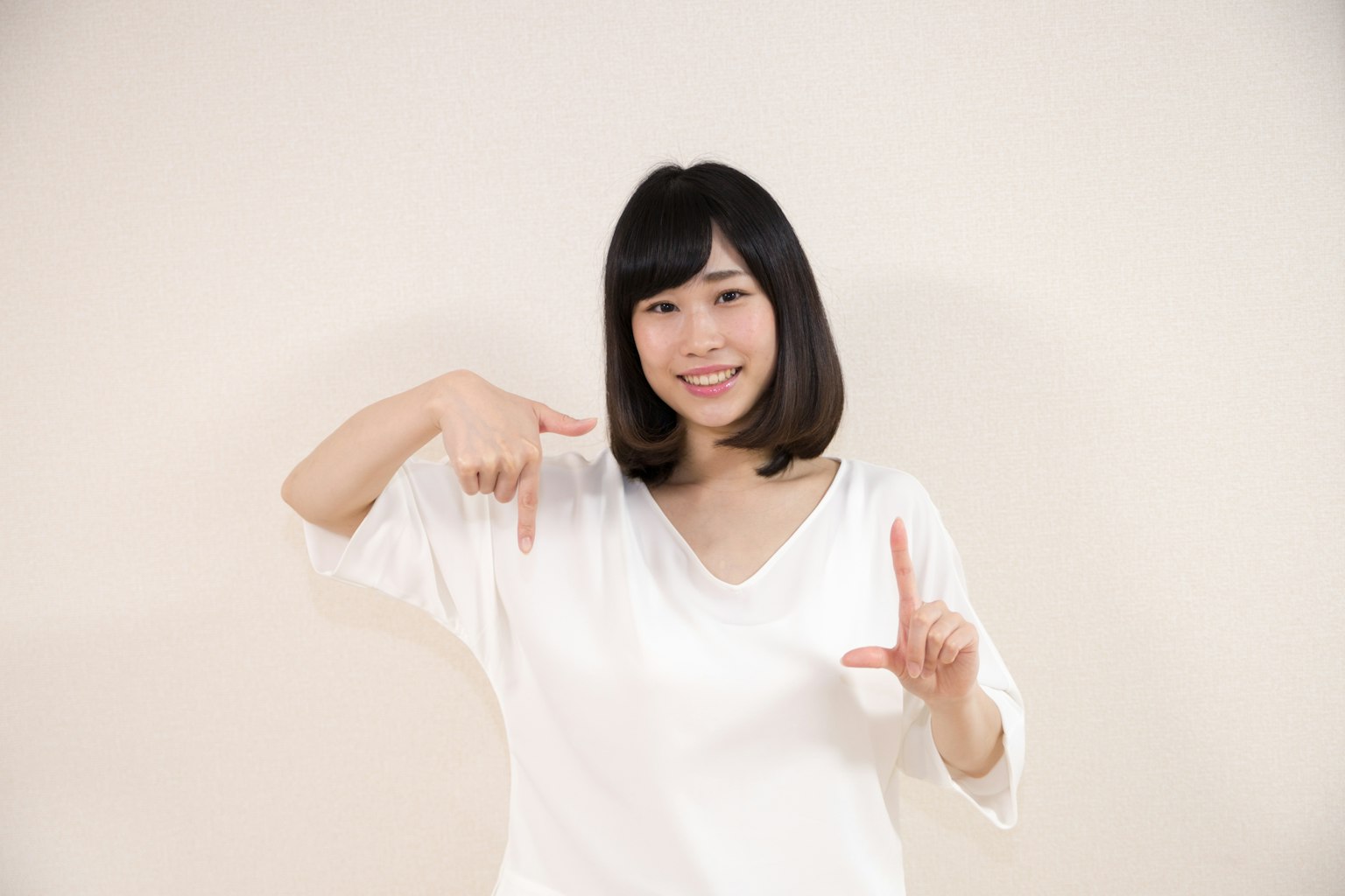 Woman in a white top posing with hands in a playful manner