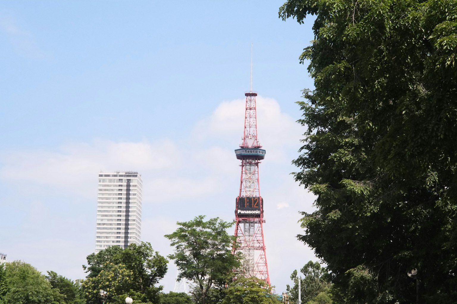 Tour de Tokyo rouge entourée d'arbres verts et d'un ciel bleu