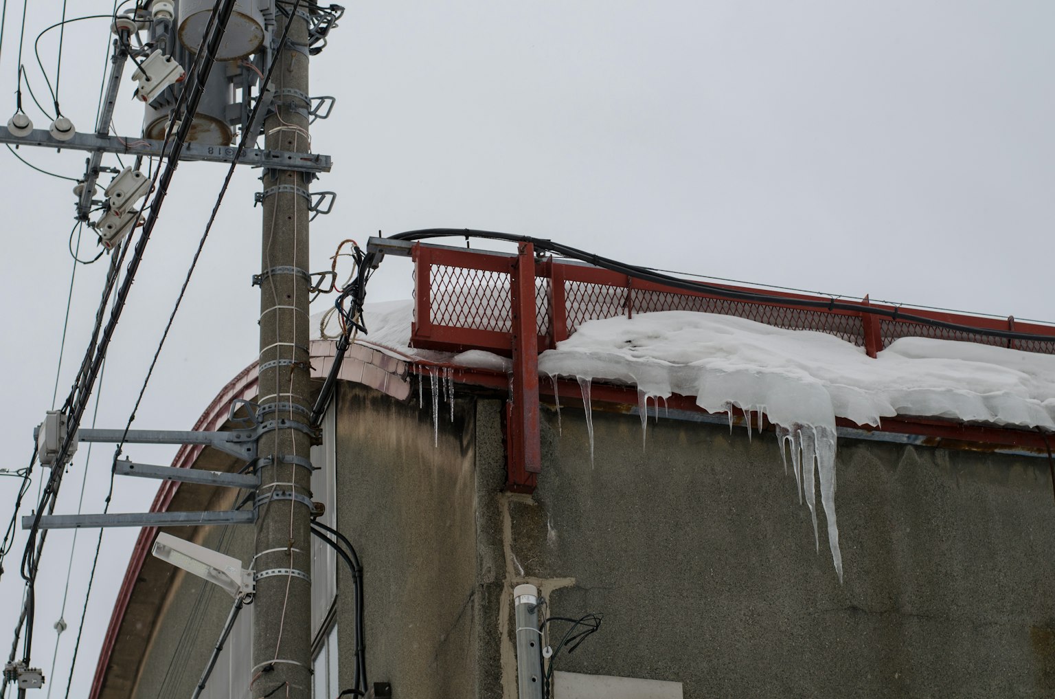 Bagian dari bangunan dengan icicles tergantung dari atap dan tiang utilitas