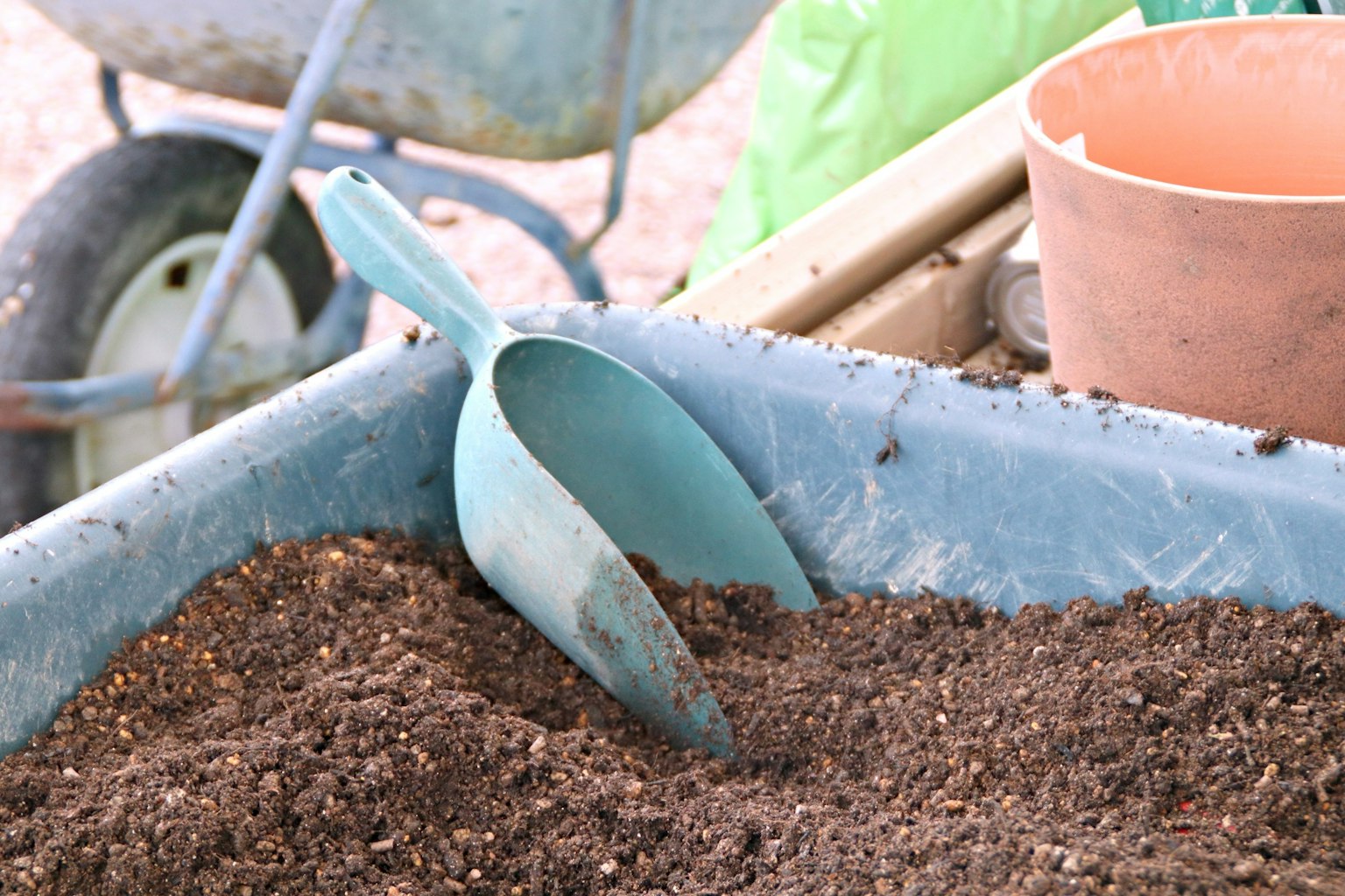 Area di giardinaggio con una paletta blu poggiata nel terreno e un vaso di terracotta