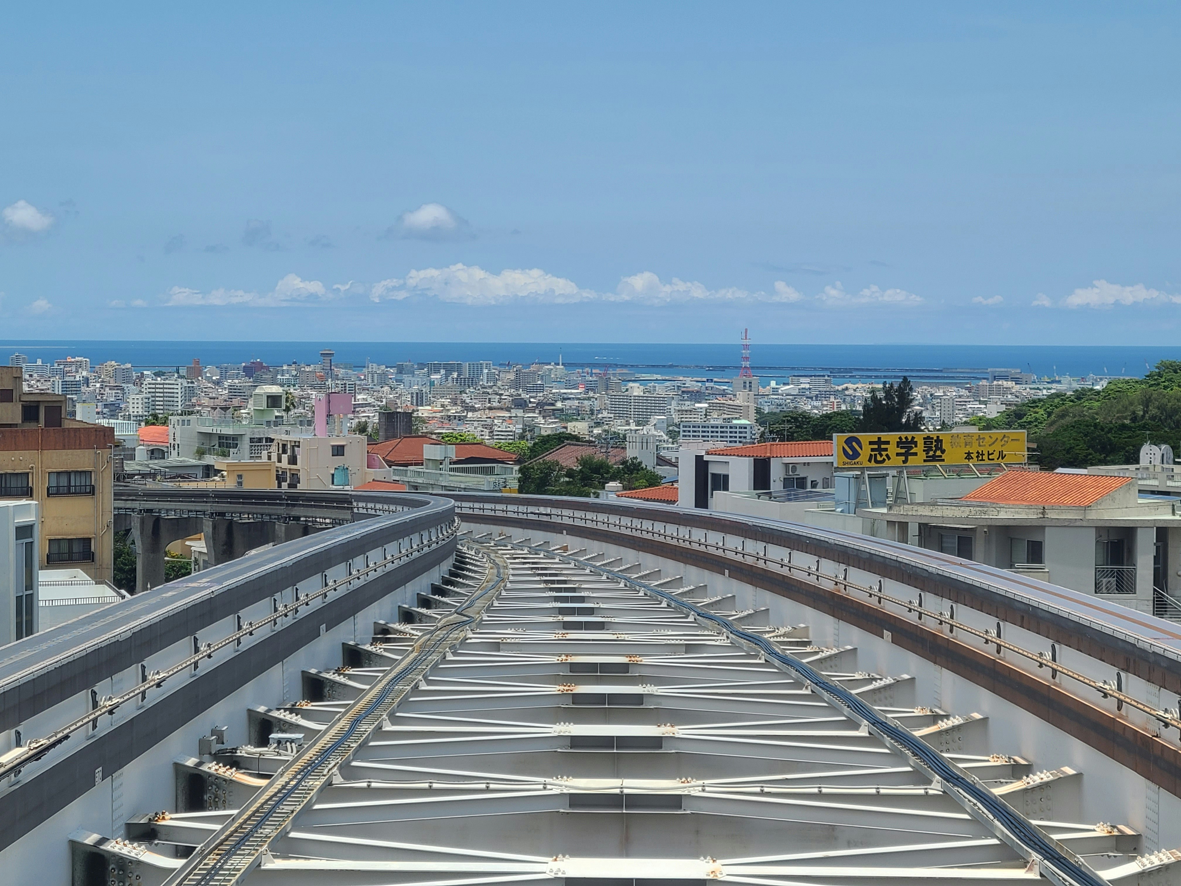 Cityscape with ocean view under blue sky featuring railway tracks