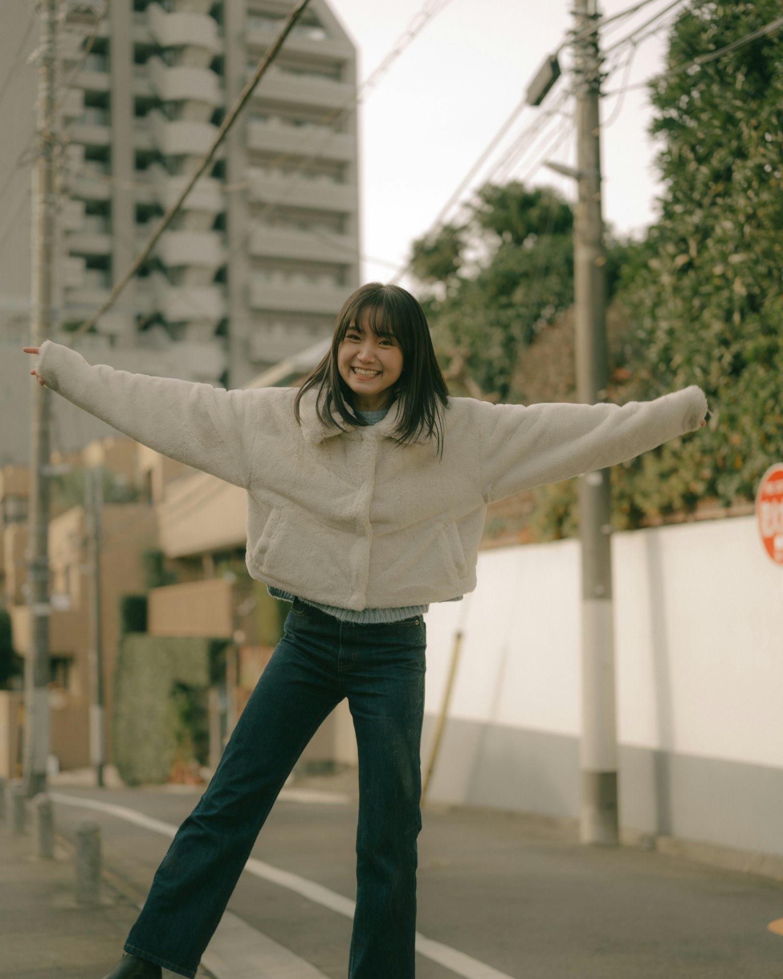 Una donna sorridente in piedi gioiosamente per strada mostrando moda casual