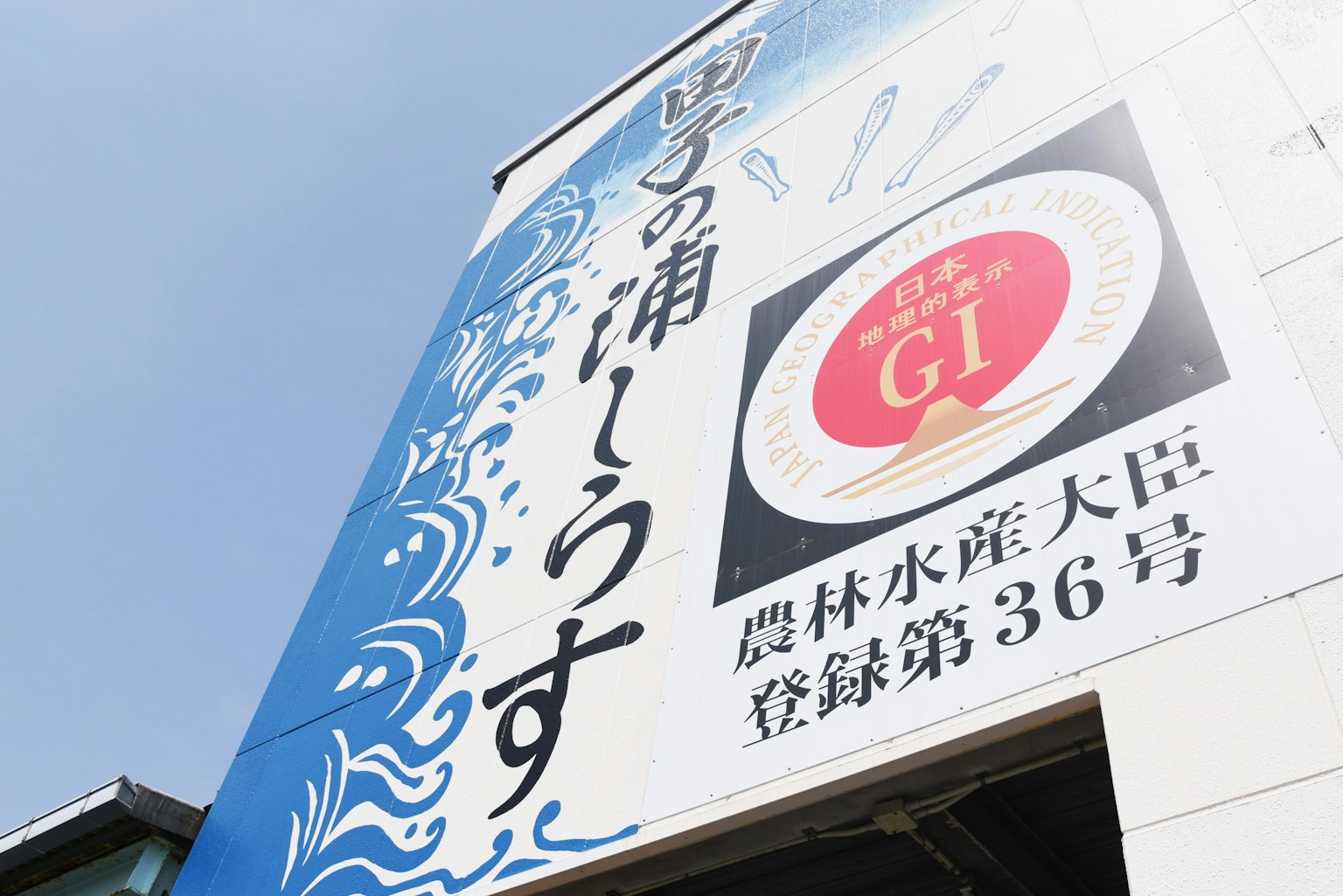 파란색 배경에 파도 디자인과 'Yokkaichi no Ura' 및 'GI'라는 텍스트가 있는 간판