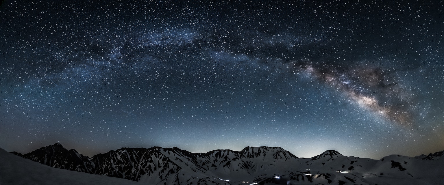 Impresionante vista panorámica de un cielo estrellado con la Vía Láctea brillante sobre montañas silueteadas