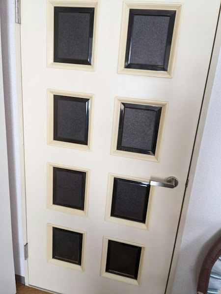 Mur intérieur avec une grille de panneaux encadrés et une poignée de porte