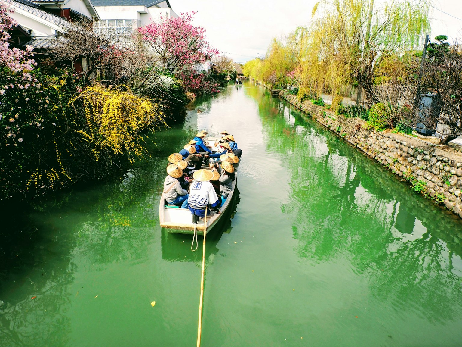 Un bote con personas navegando por un canal verde rodeado de flores en flor