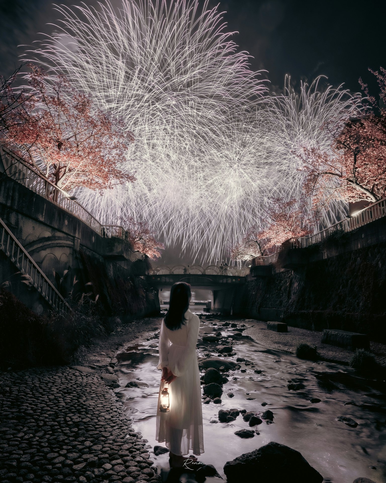 一位穿著白色連衣裙的女性站在河邊,仰望夜空中的煙花