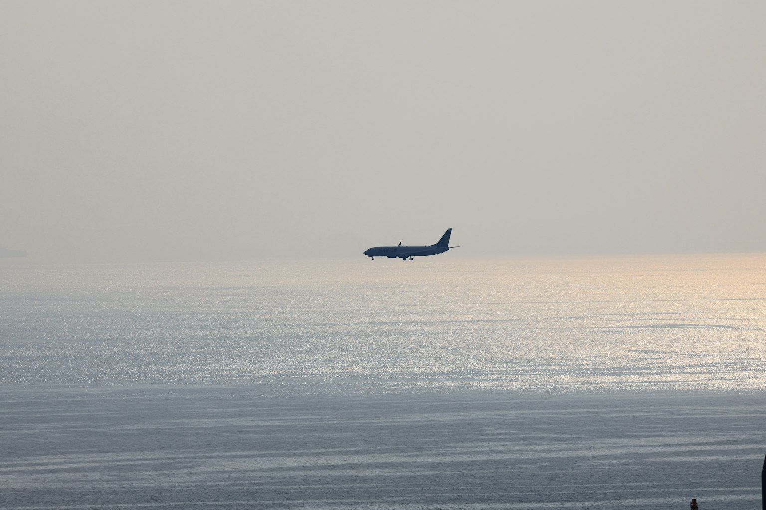 Silhouette di un aereo che vola sopra l'oceano