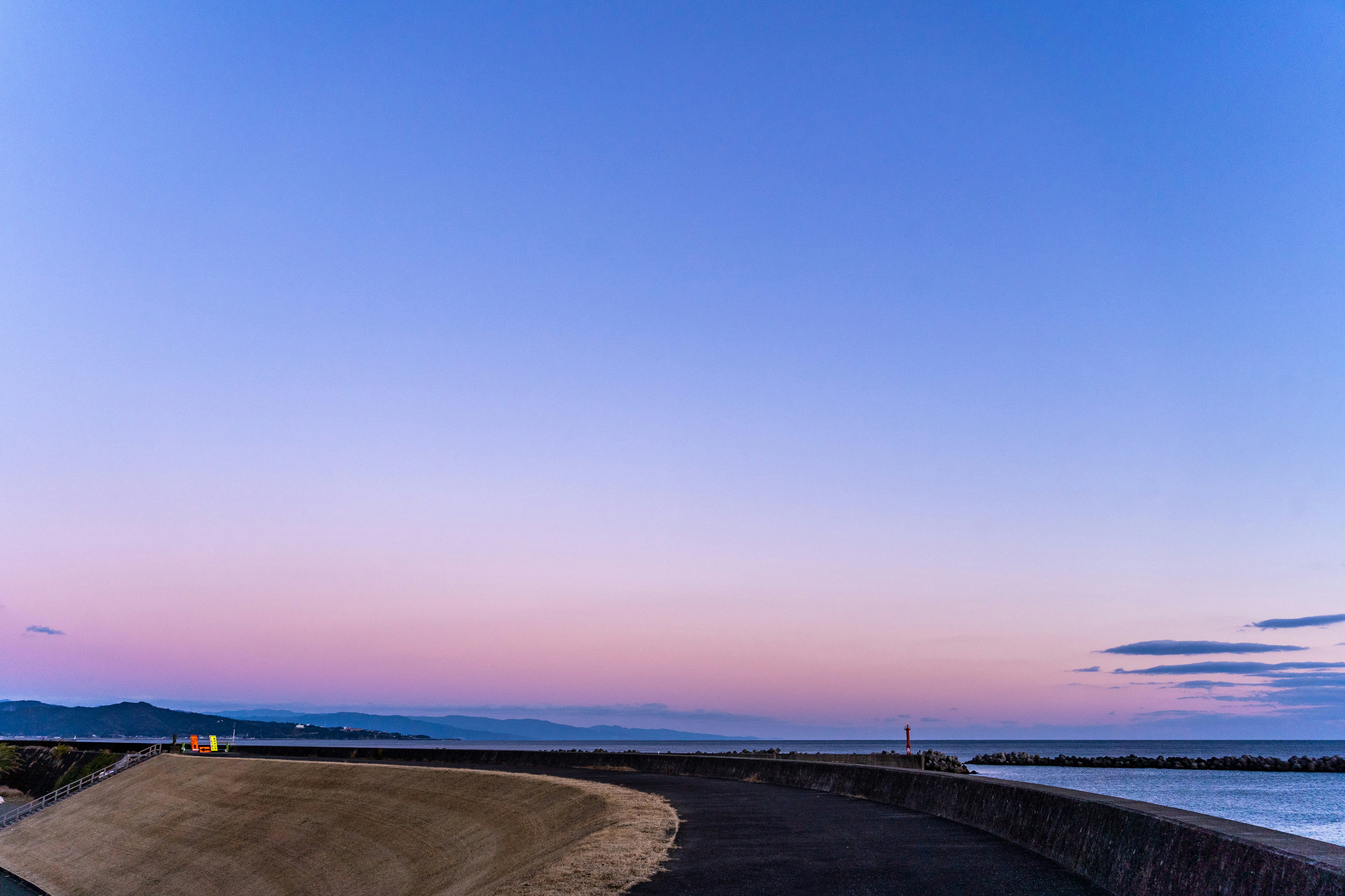 夕焼けの海沿いの防波堤と曲がり道