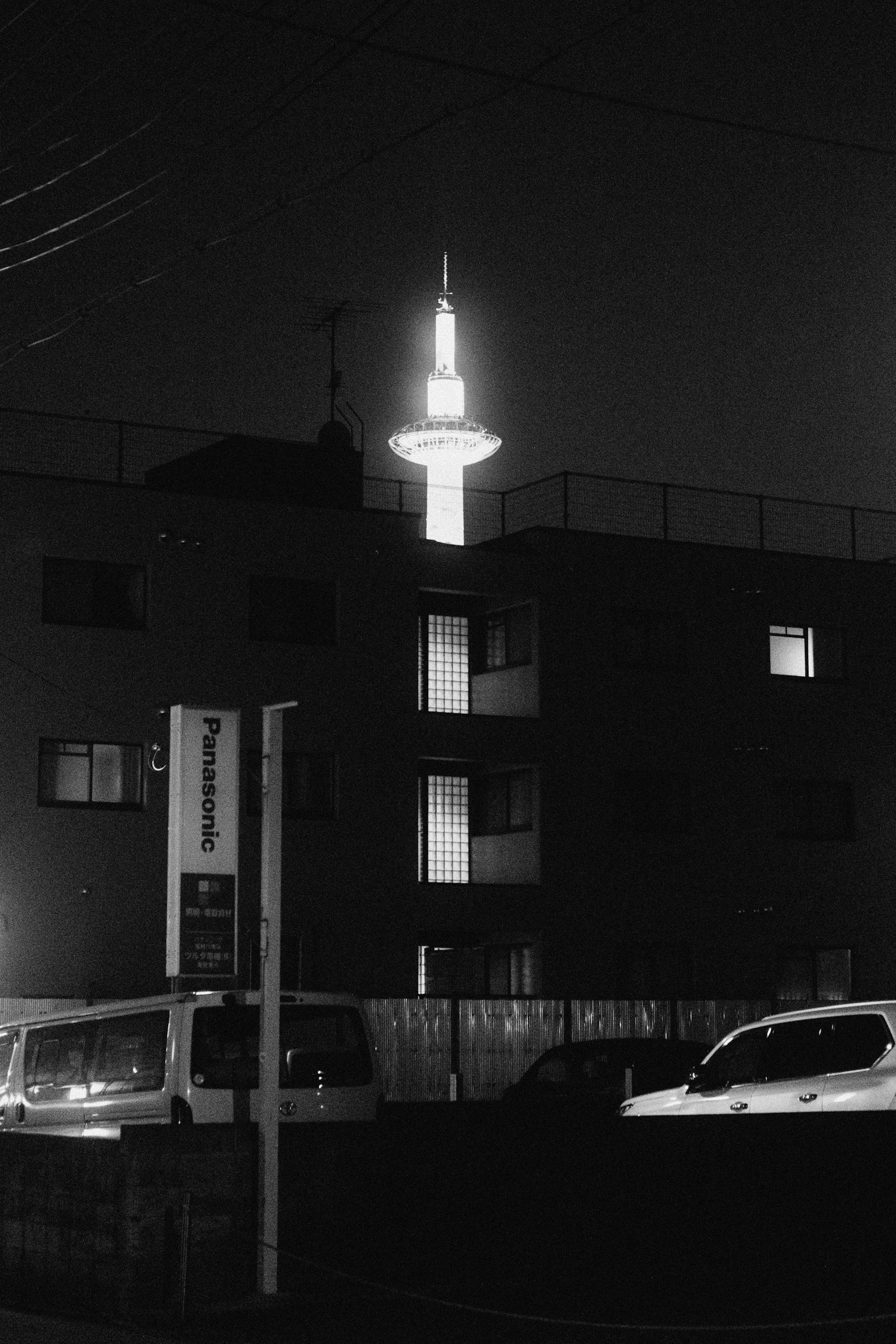Illuminated tower rising above buildings at night