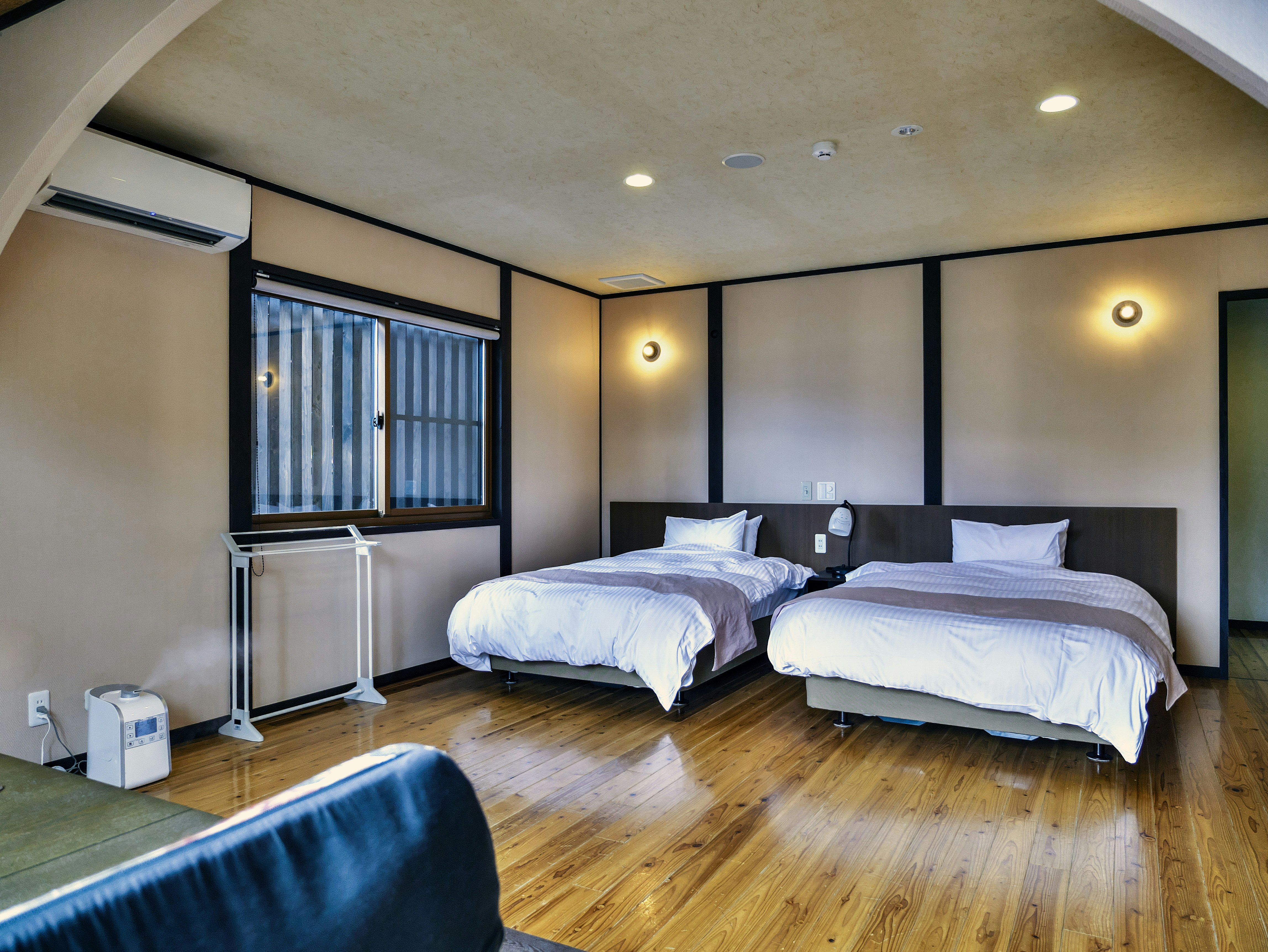 Interior kamar bergaya Jepang modern dengan dua tempat tidur dan pencahayaan tidak langsung yang hangat