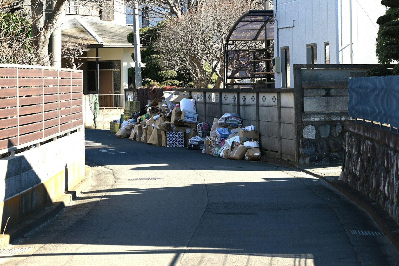 Rue étroite avec des sacs poubelles empilés et des maisons environnantes