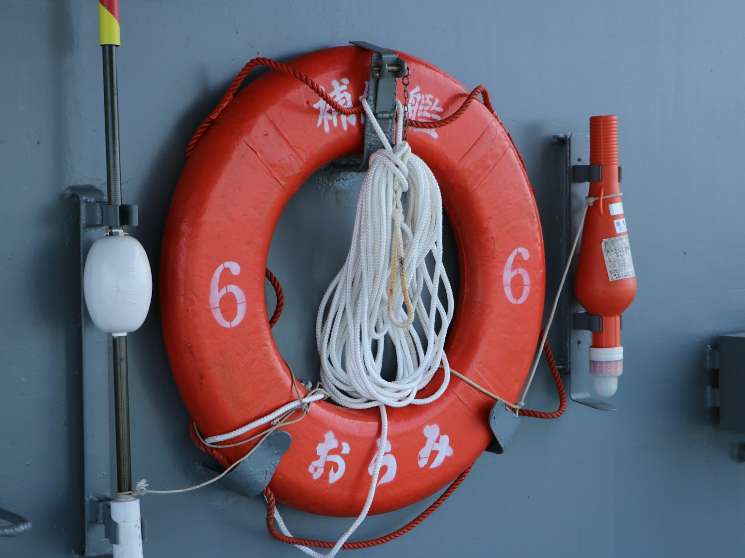 Rote Rettungsboje mit Seil an einer Wand befestigt