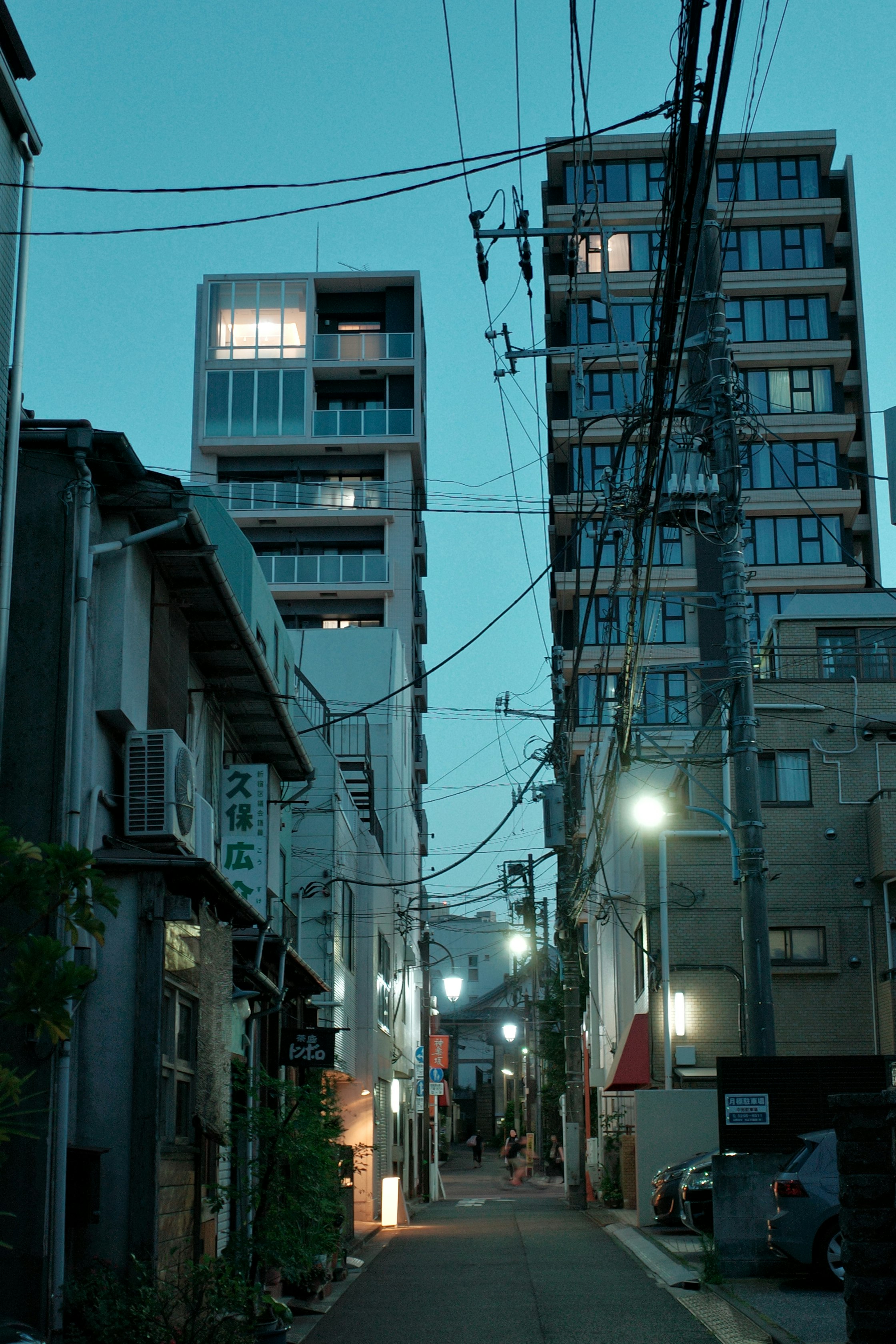 路地の電線と高層アパートが並ぶ夜の街並み