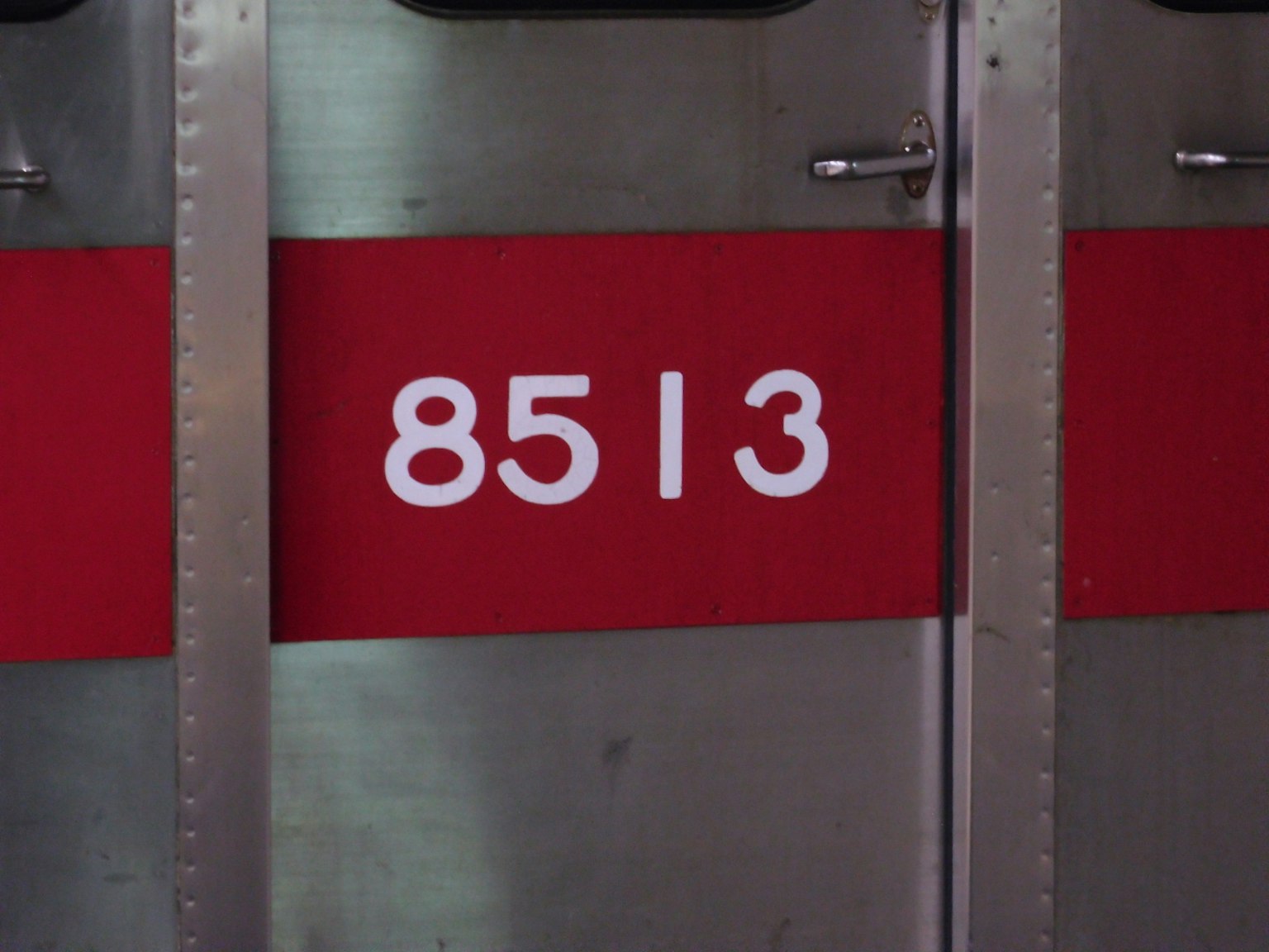 Metal door with a red stripe displaying the white number 8513