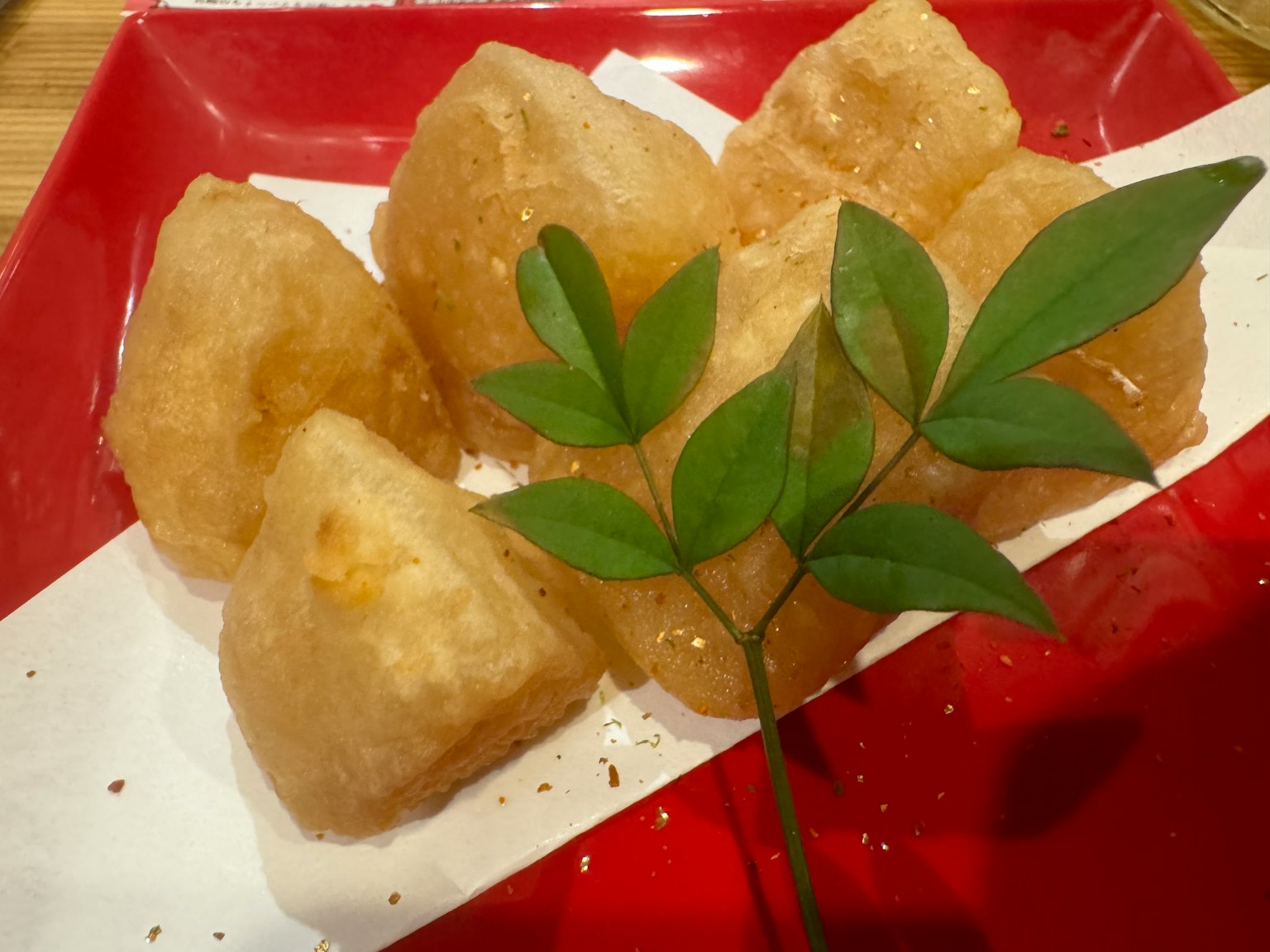 Makanan berbentuk pangsit goreng yang disusun di atas piring merah
