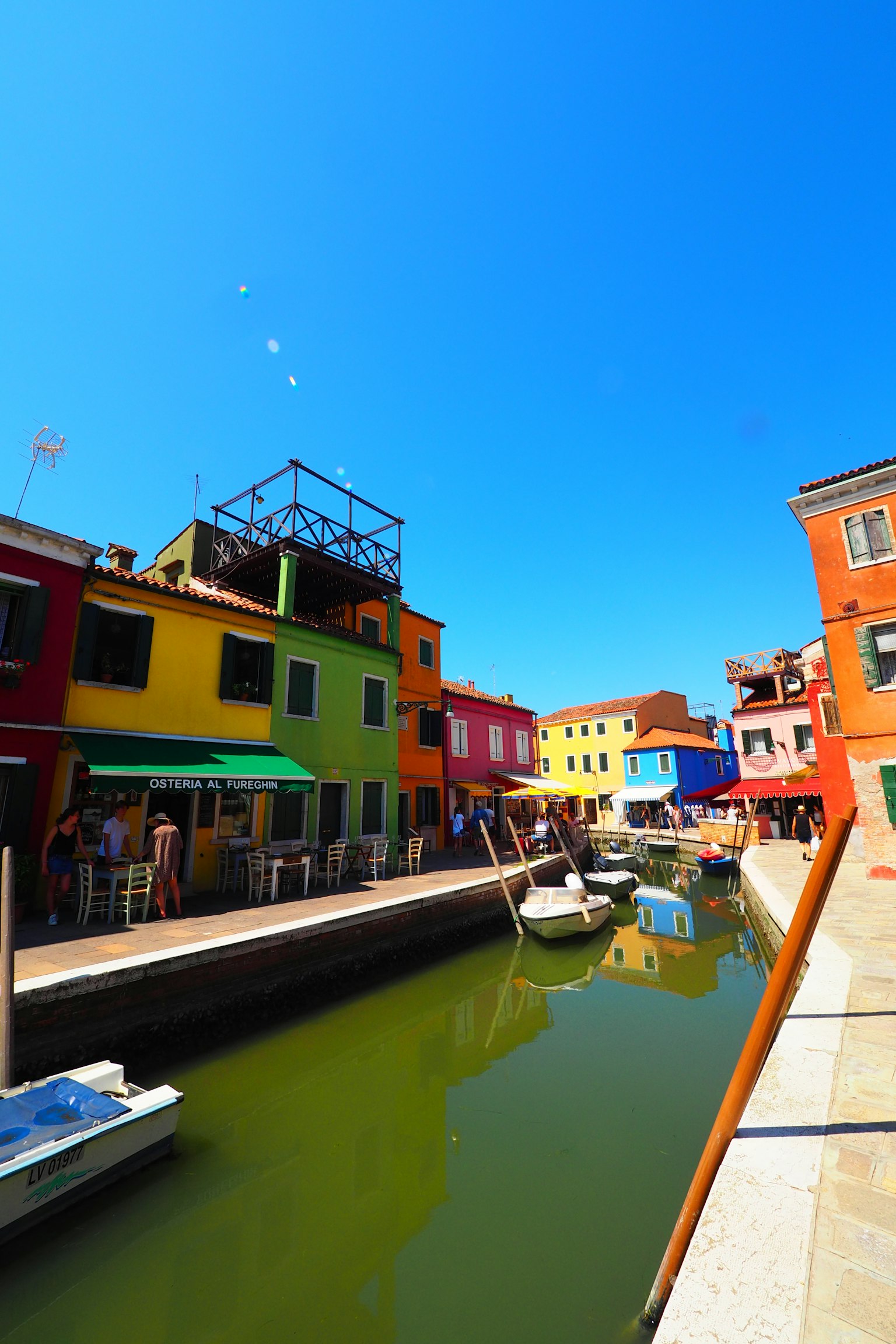 Bunte Gebäude entlang eines Kanals in Burano bei strahlendem Sonnenschein