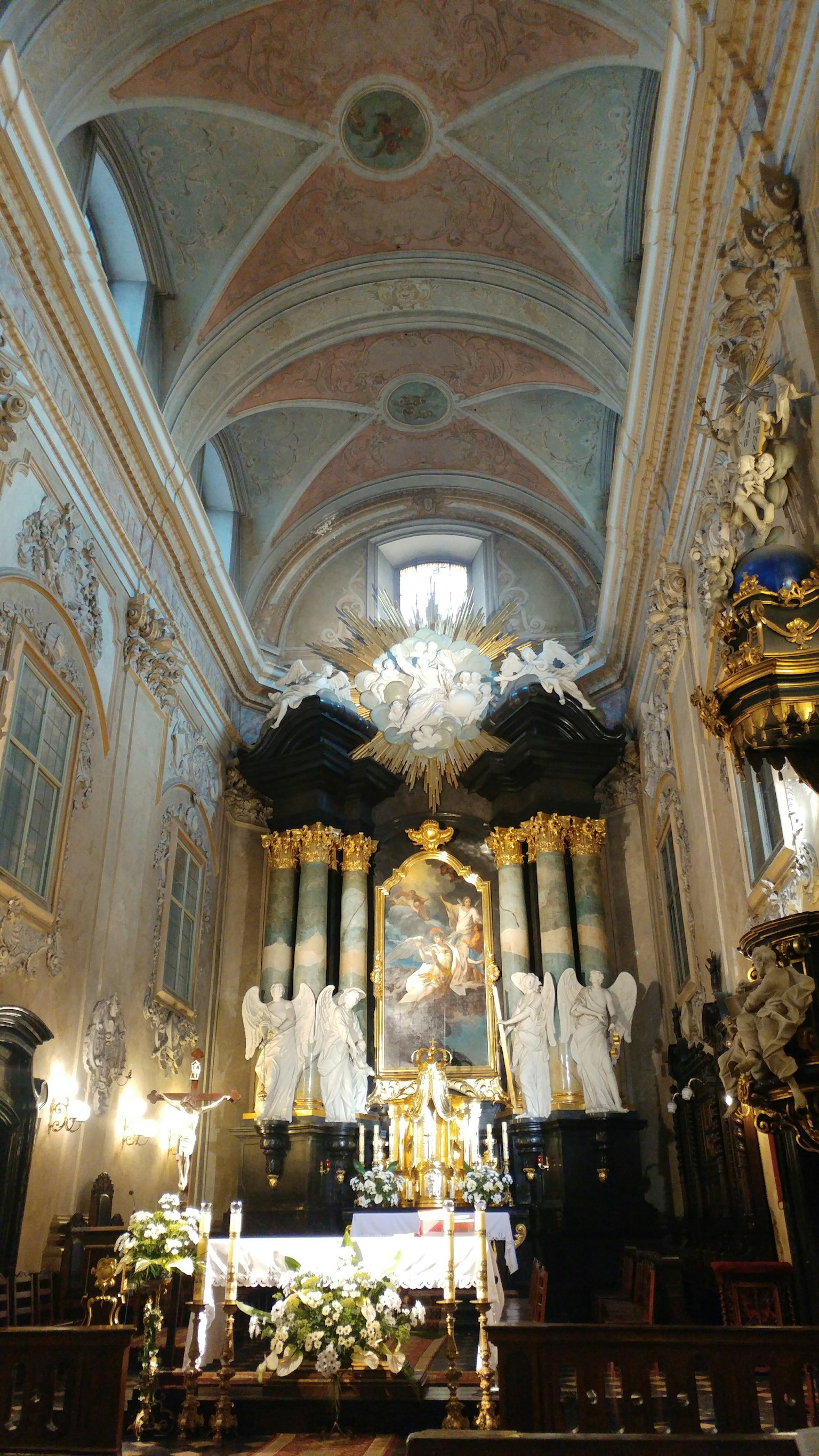Hermoso interior de una iglesia con arcos decorativos en el techo pinturas religiosas en las paredes y flores adornando el altar