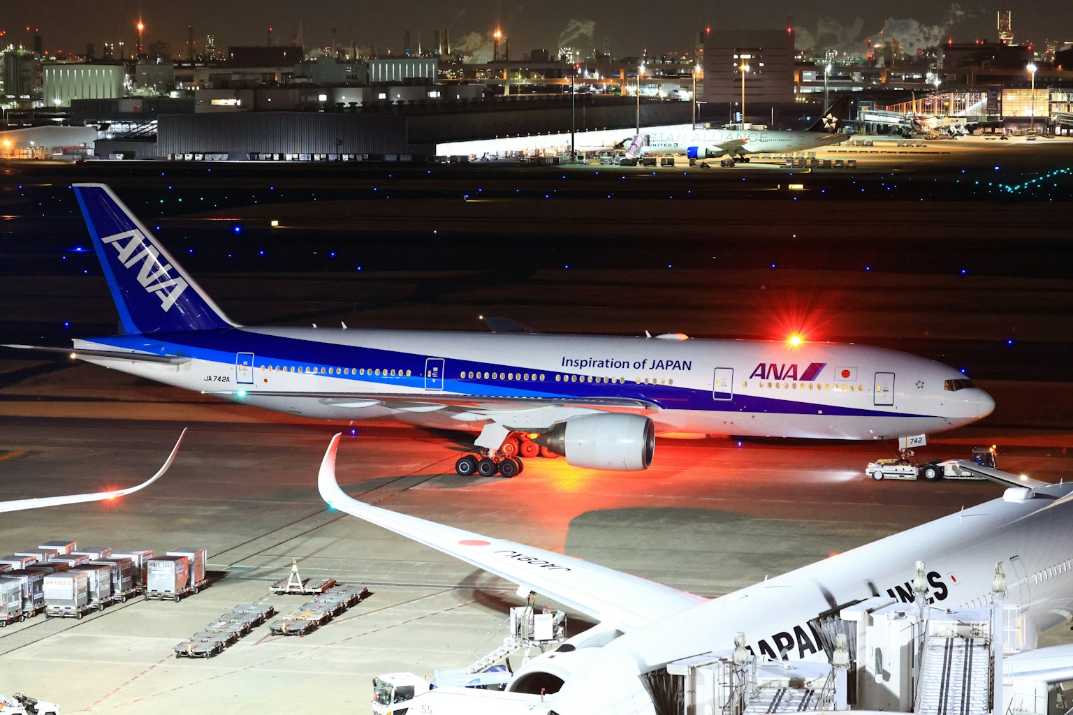 Avion ANA sur la piste la nuit avec des lumières d'aéroport