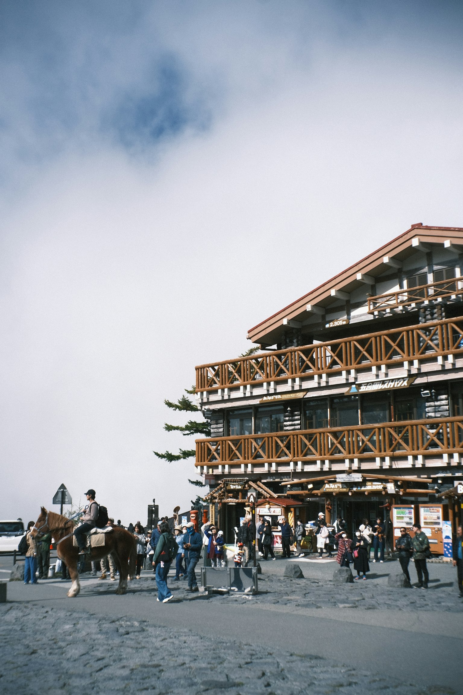 กระท่อมในภูเขากับผู้คนที่รวมตัวกันและคนที่ขี่ม้า