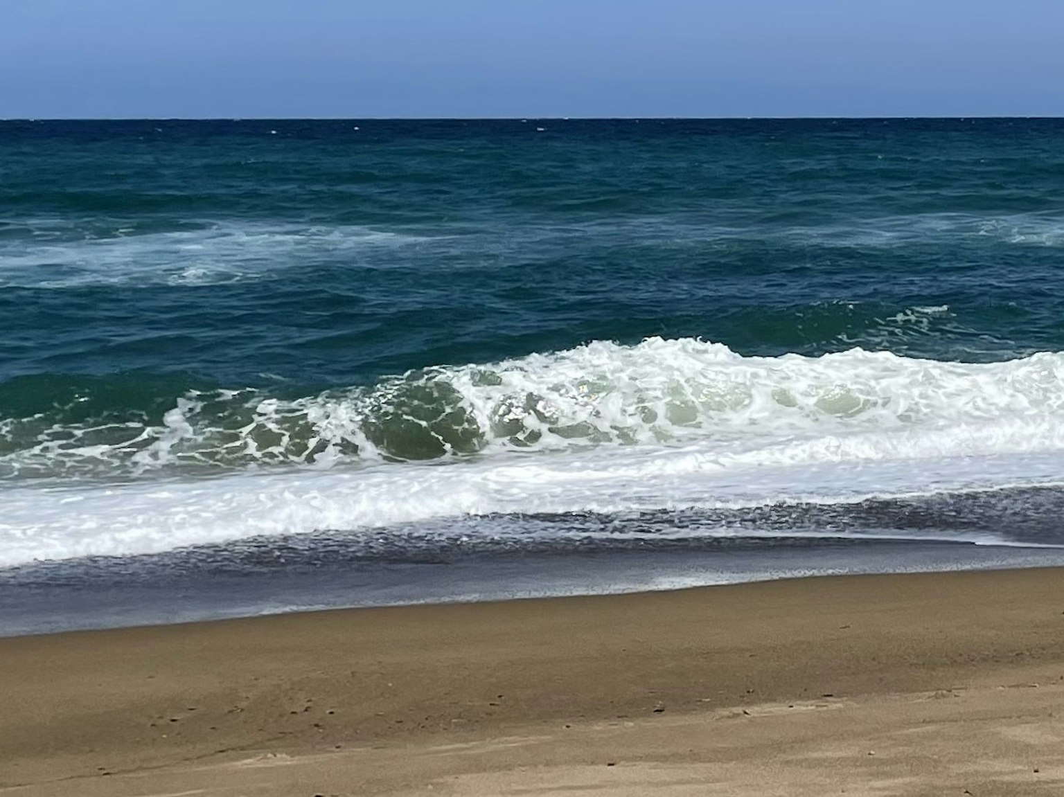 Vue pittoresque d'une plage de sable avec des vagues déferlantes et un océan bleu