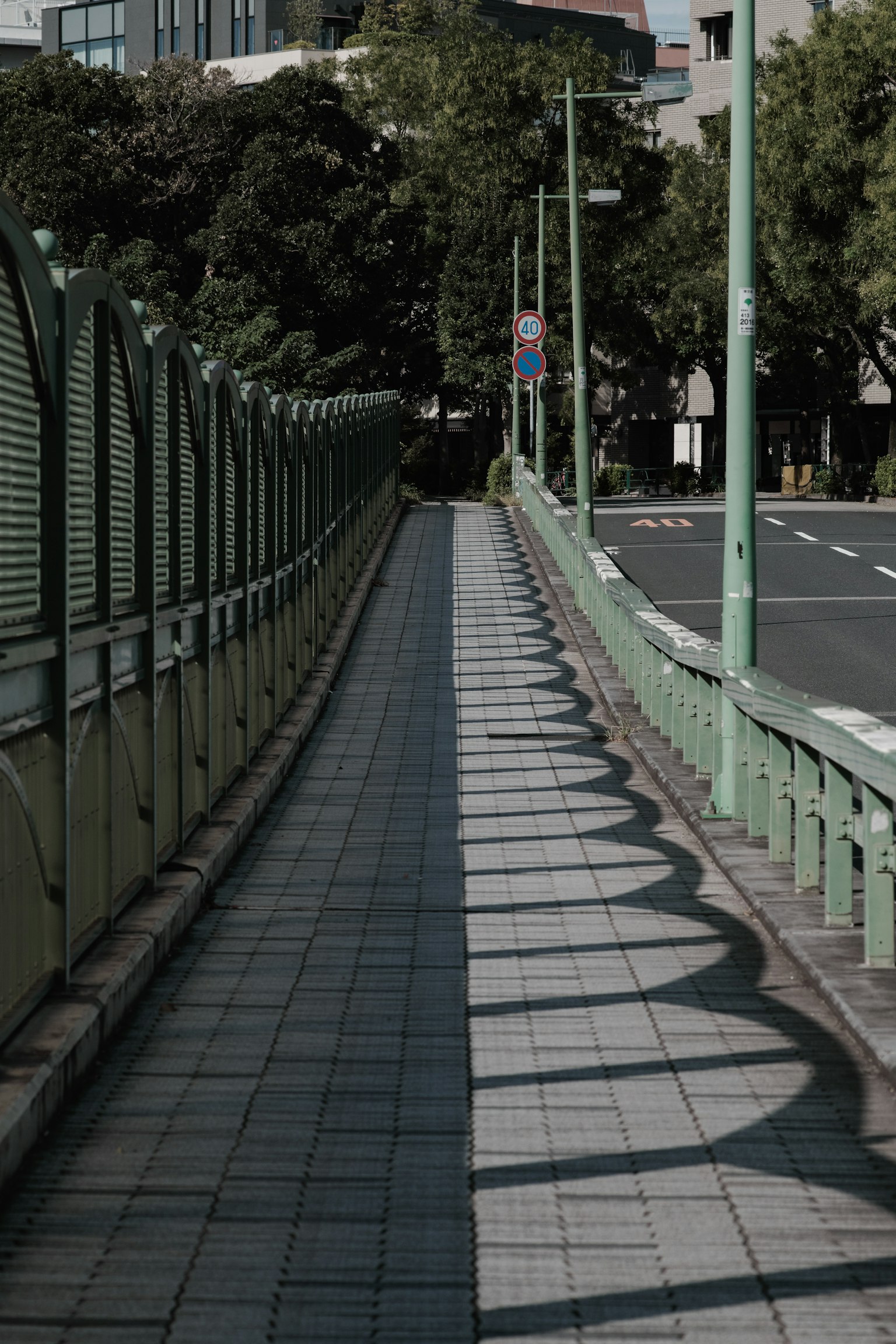 Paisaje urbano con una cerca verde y una acera de baldosas