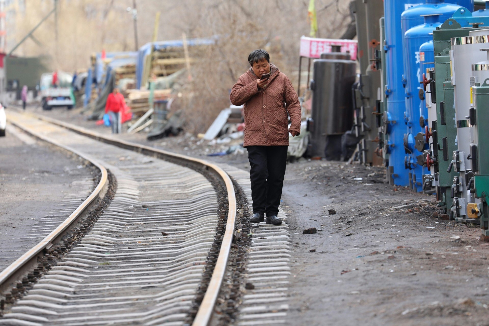 railway trackside scene with a person walking and blue equipment