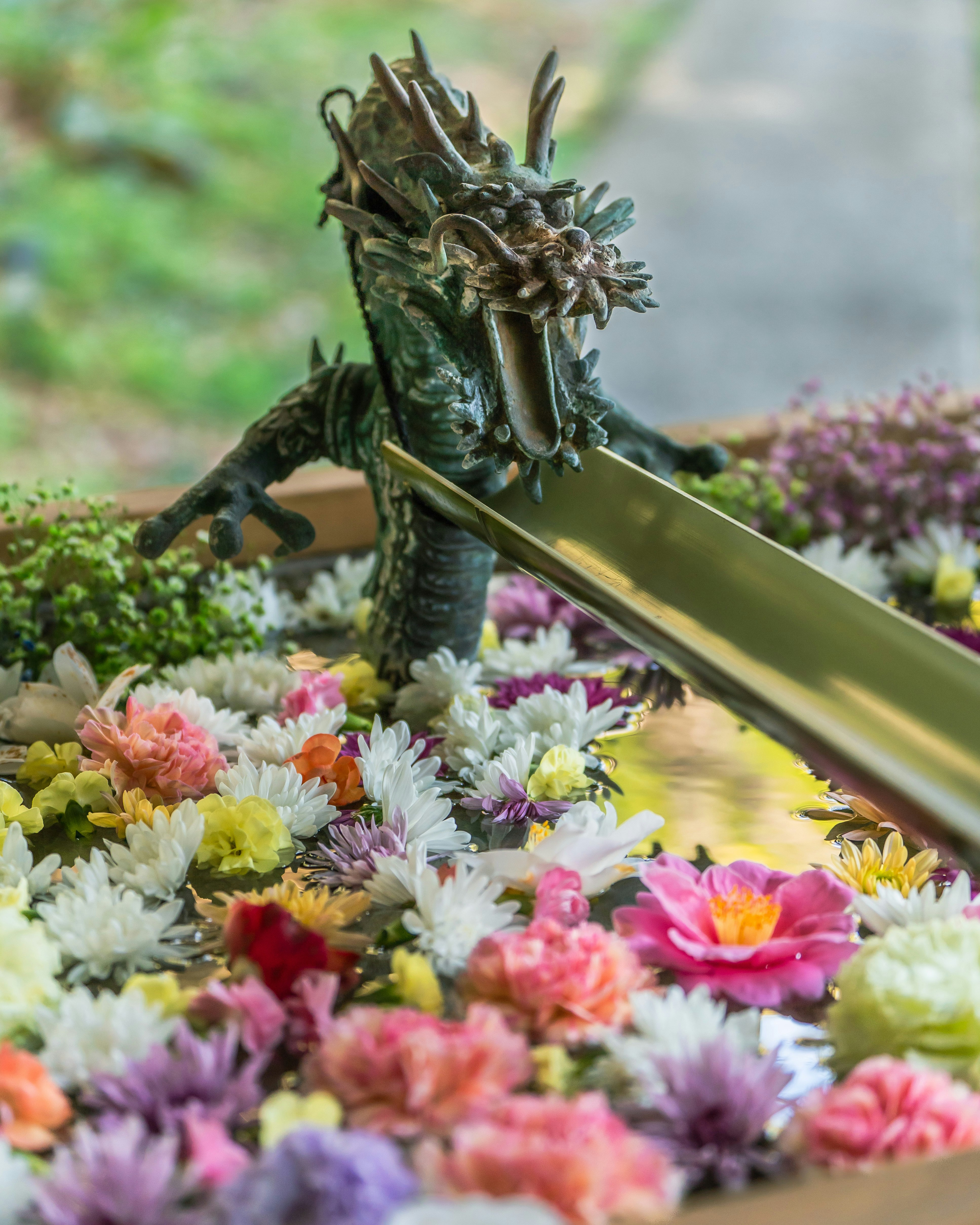 花に囲まれたドラゴンの像と剣