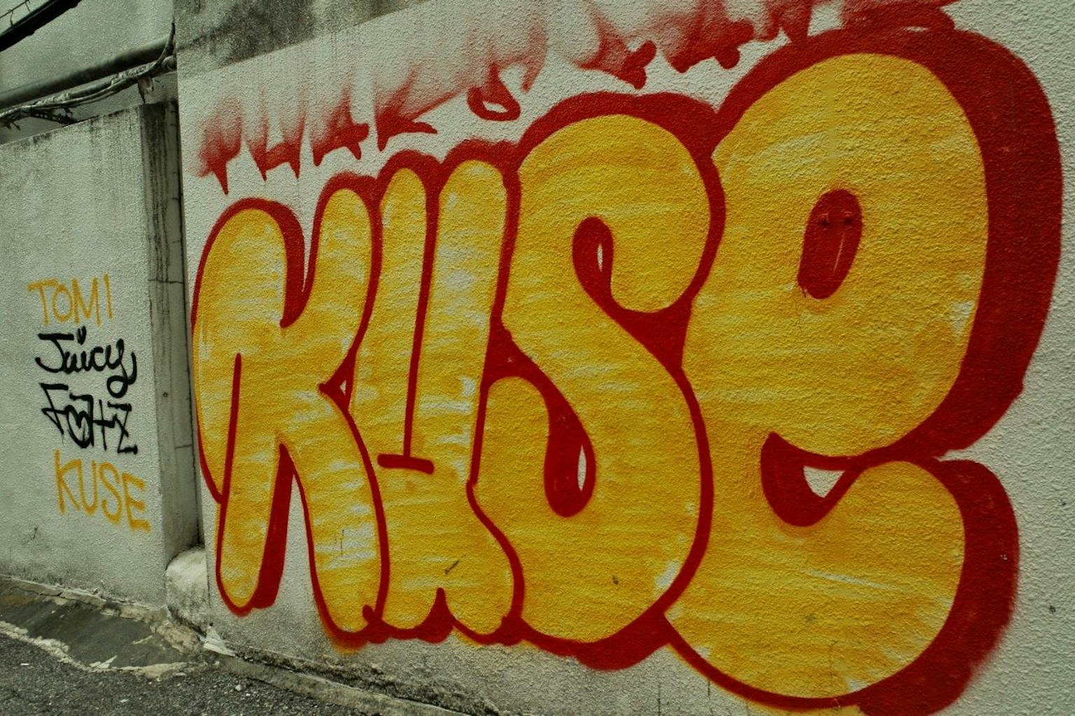 벽에 그려진 큰 노란색 그래피티 아트 'KUSE'