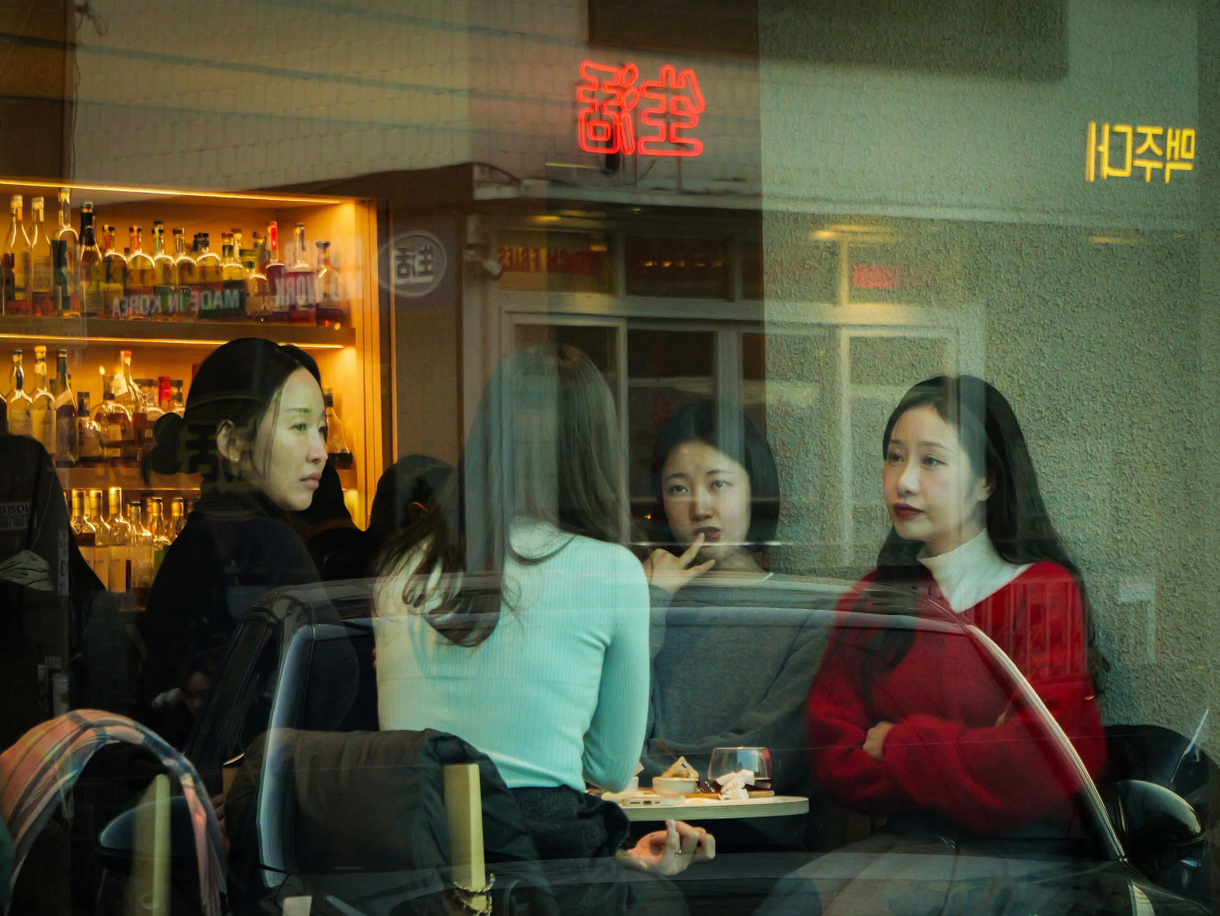 donne che chiacchierano in un bar viste attraverso una finestra