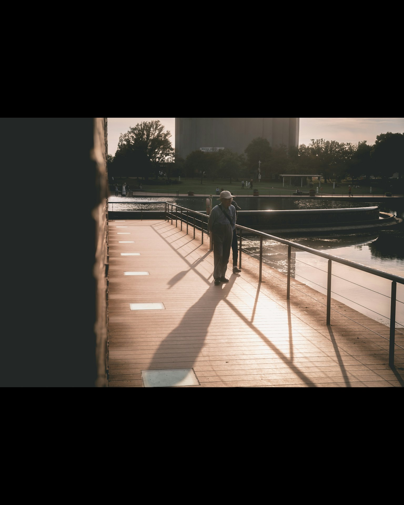 Eine Person, die bei Sonnenuntergang auf einem Uferdeck geht und einen langen Schatten wirft
