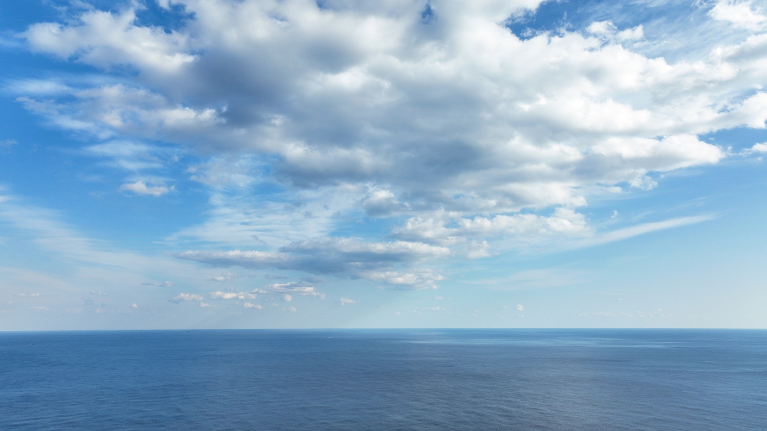 Vista calma dell'oceano con cielo blu e nuvole bianche