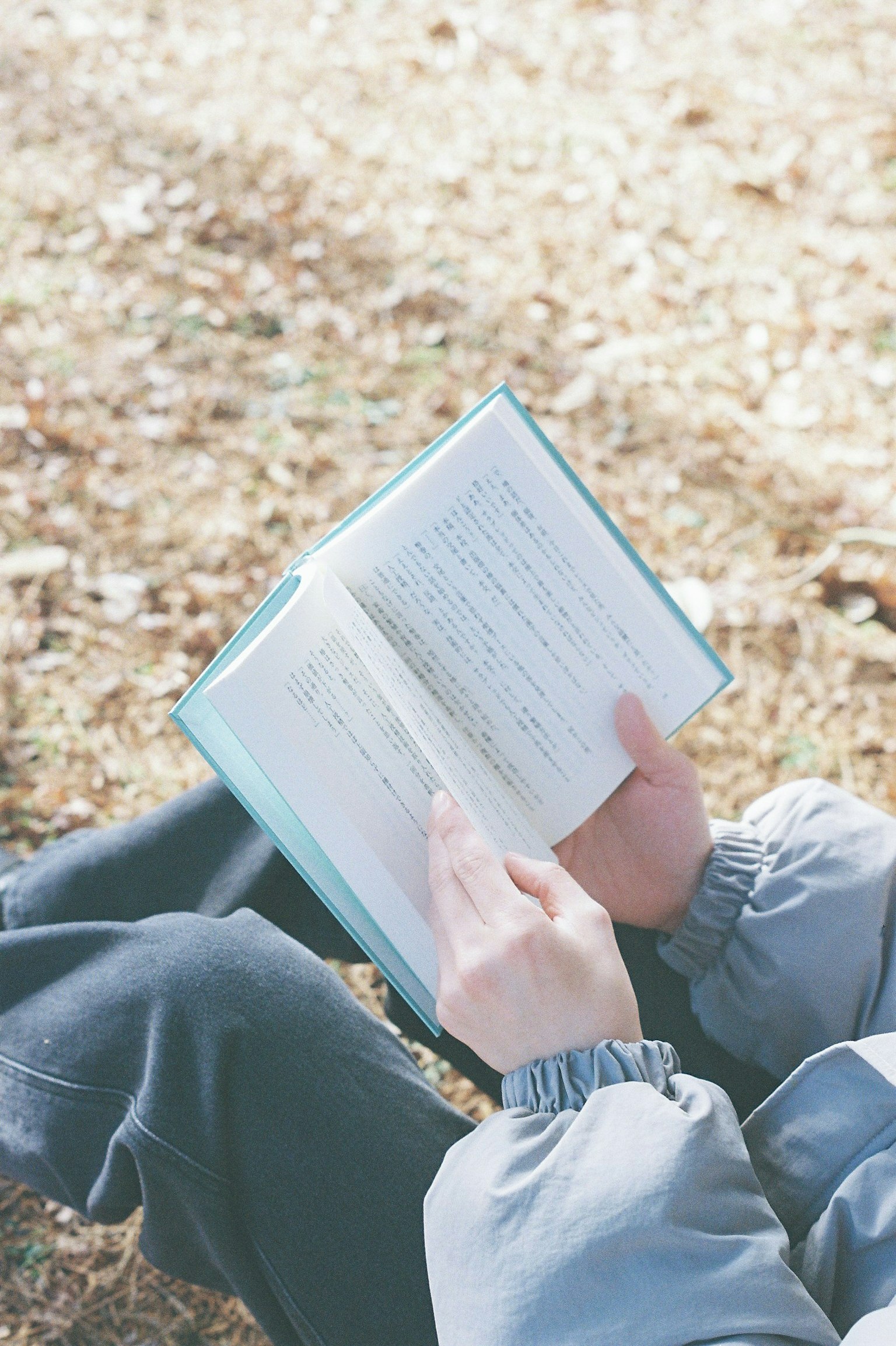 Persona sosteniendo un libro y pasando las páginas en un entorno exterior sereno