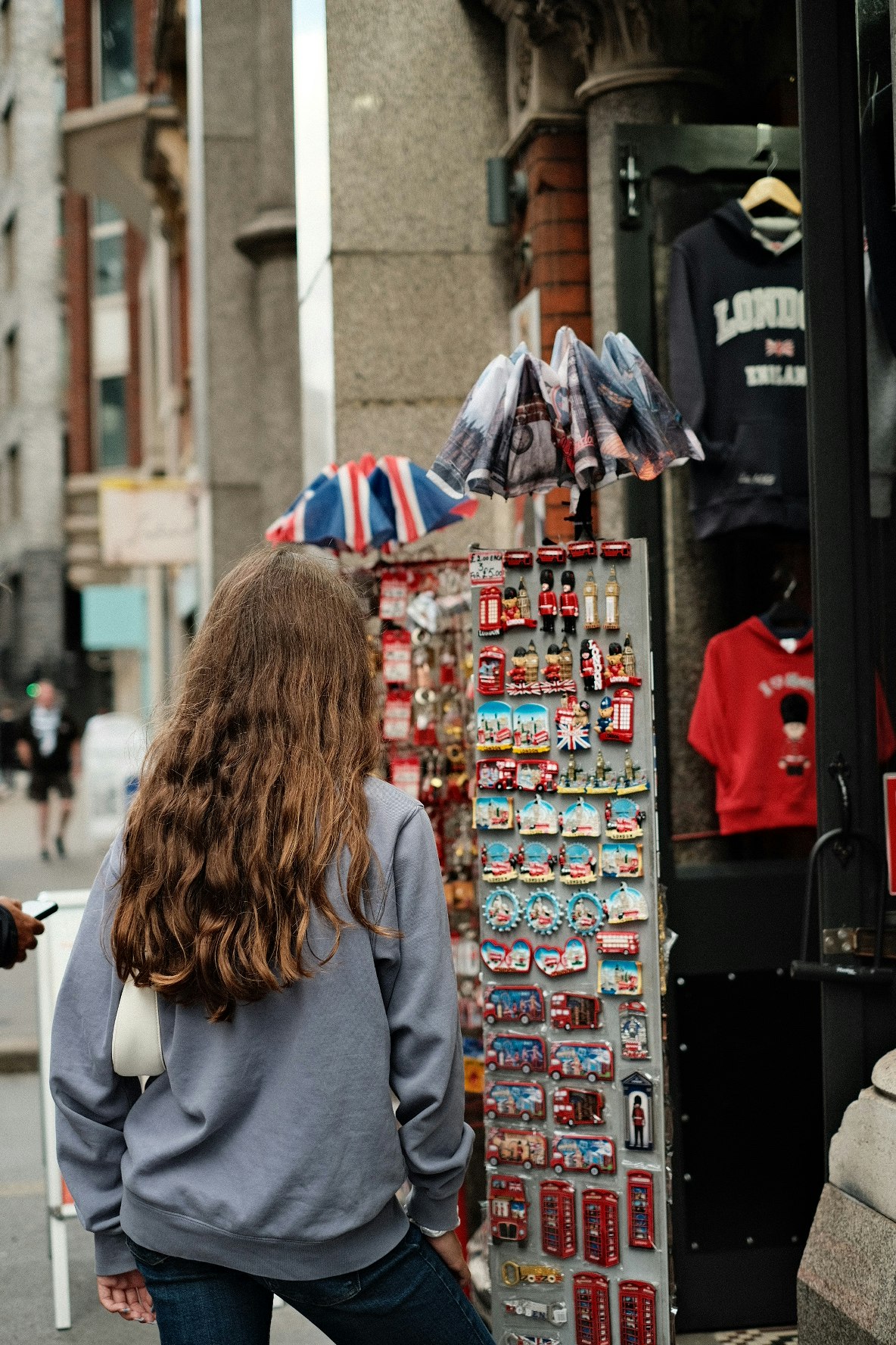 souvenir shop display of keychains and trinkets in a narrow street