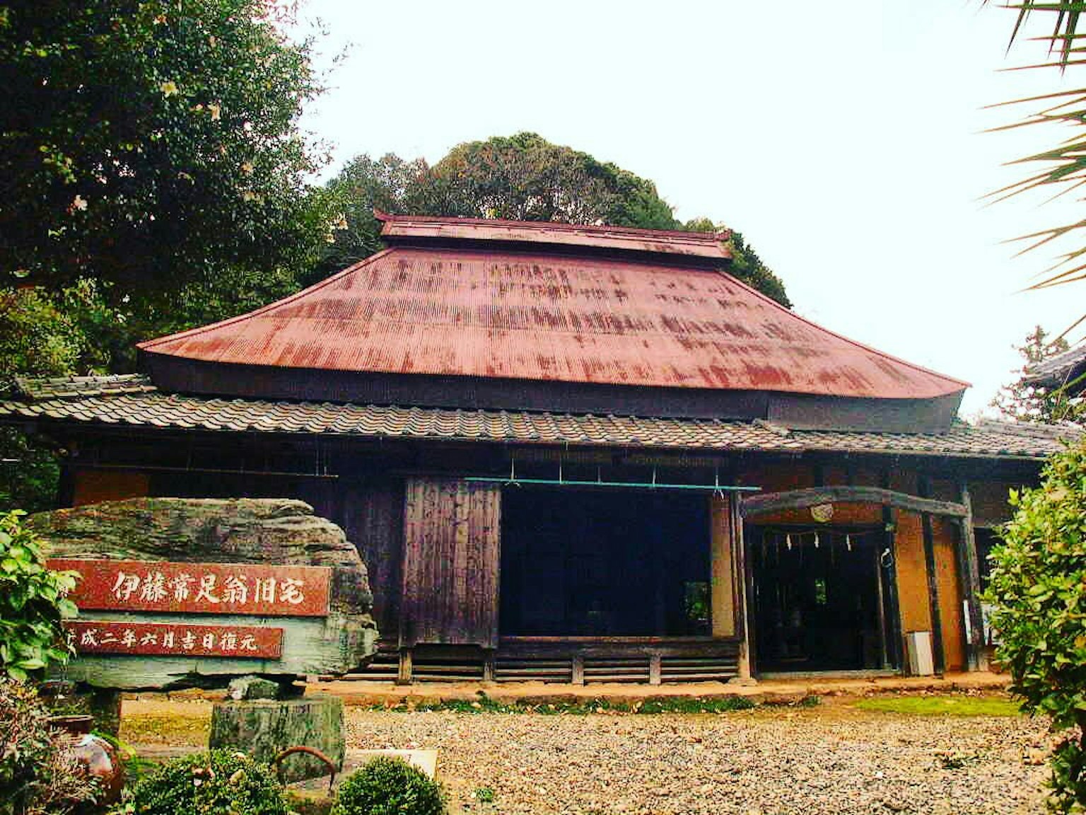 บ้านสไตล์ญี่ปุ่นดั้งเดิมหลังคาสีแดงและผนังไม้ล้อมรอบด้วยสวนที่สวยงาม