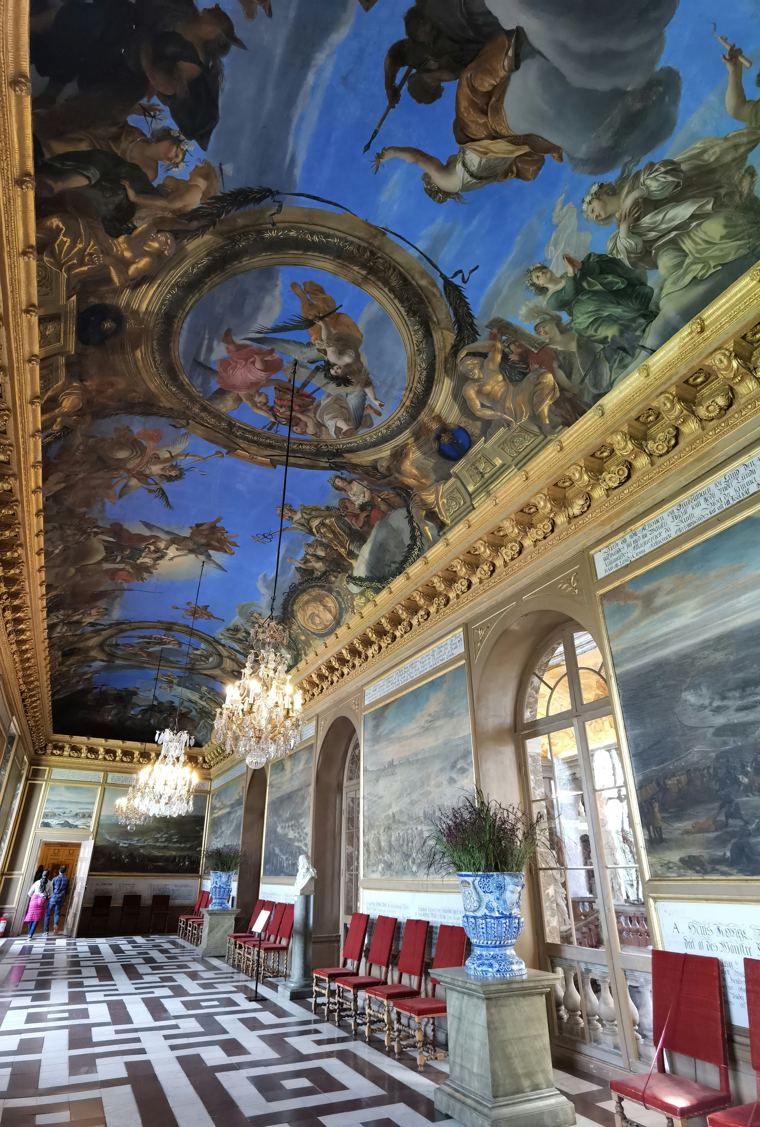 interior of an ornate hall with ceiling fresco and chandeliers