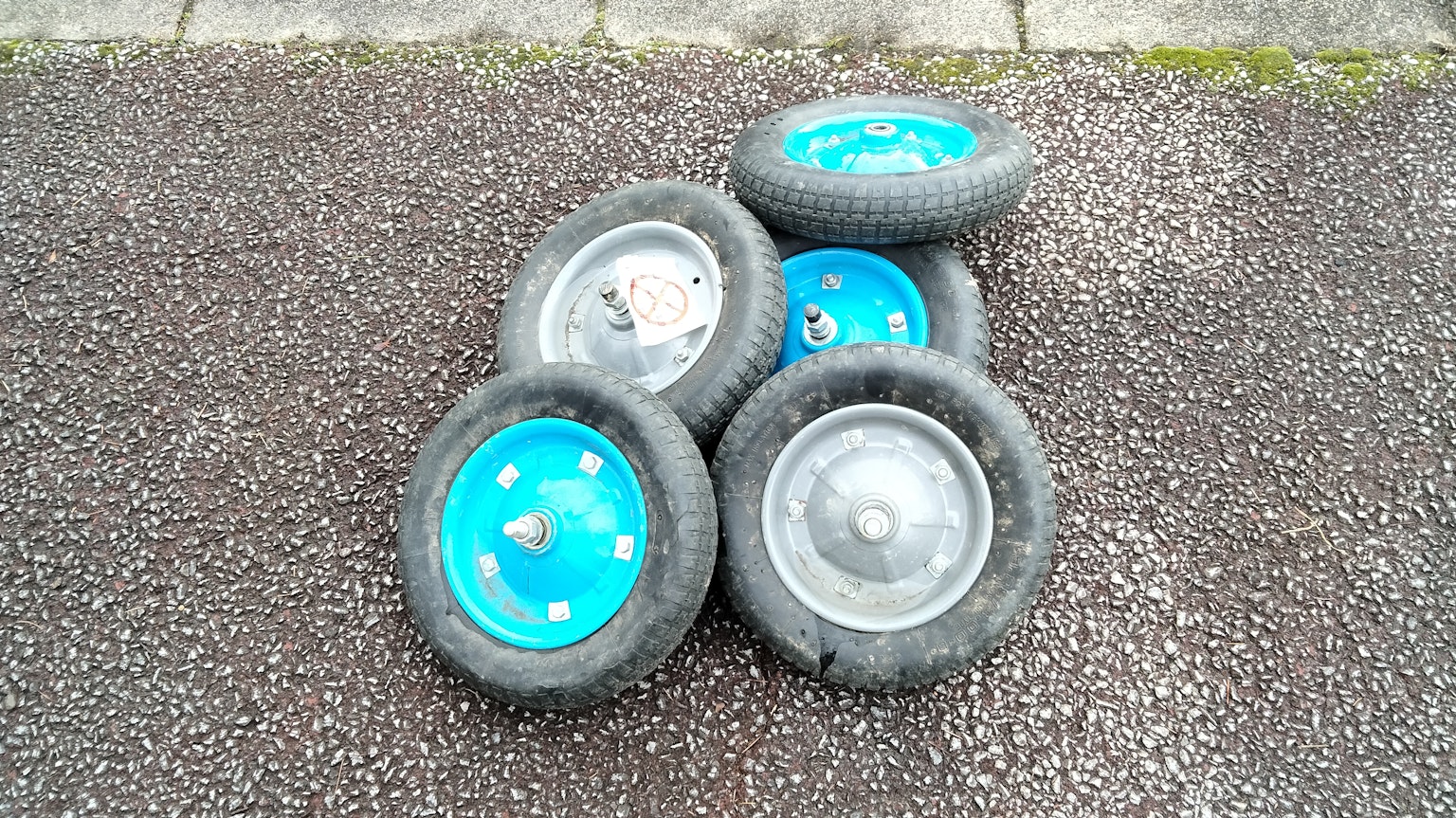 Stack of blue wheels with black tires on a textured surface