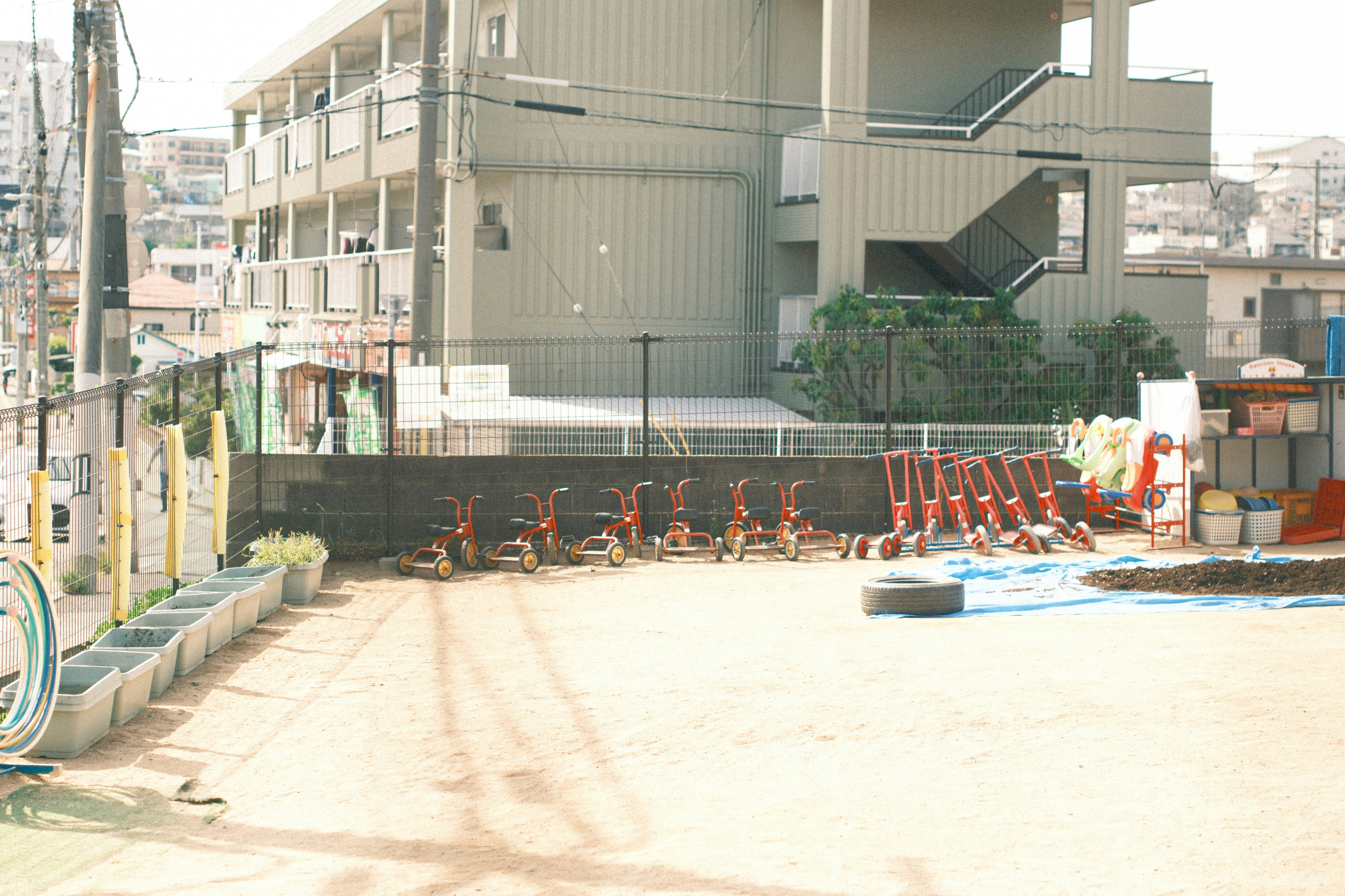屋外の壁際に並ぶ自転車と園芸用具のある作業スペース