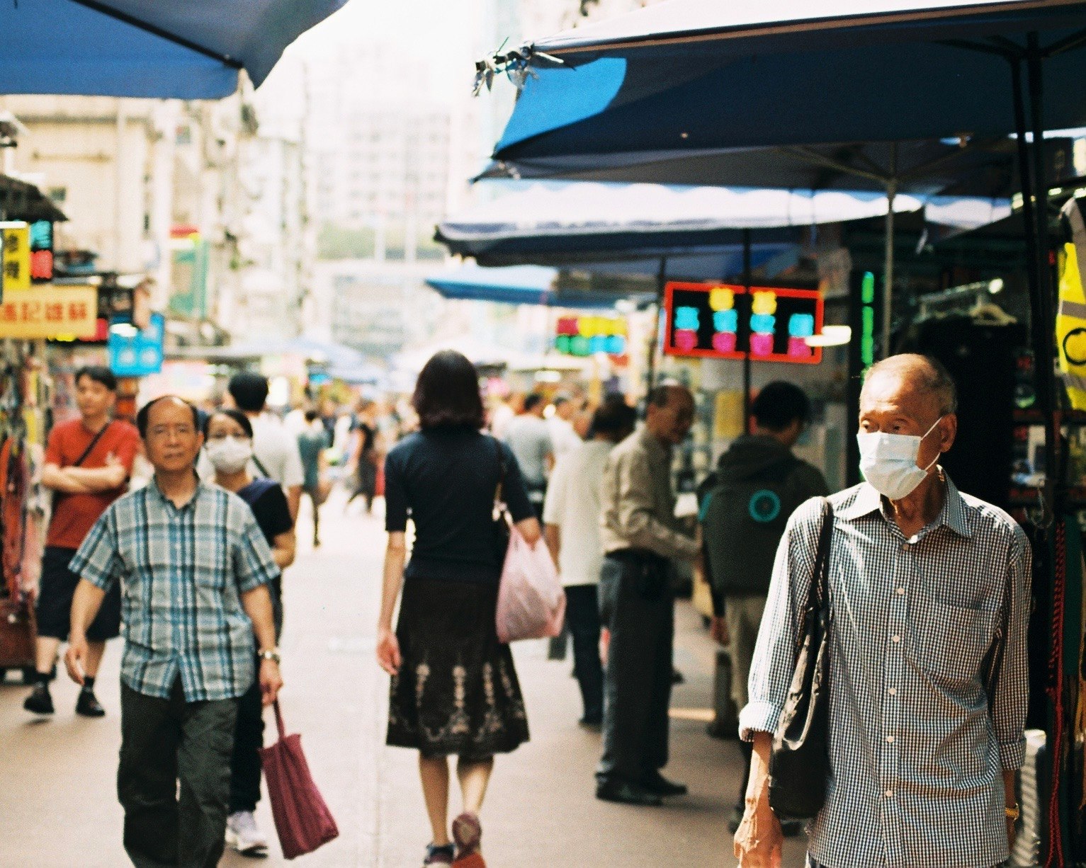 사람들이 걷고 있는 분주한 시장 거리와 마스크를 쓴 남자