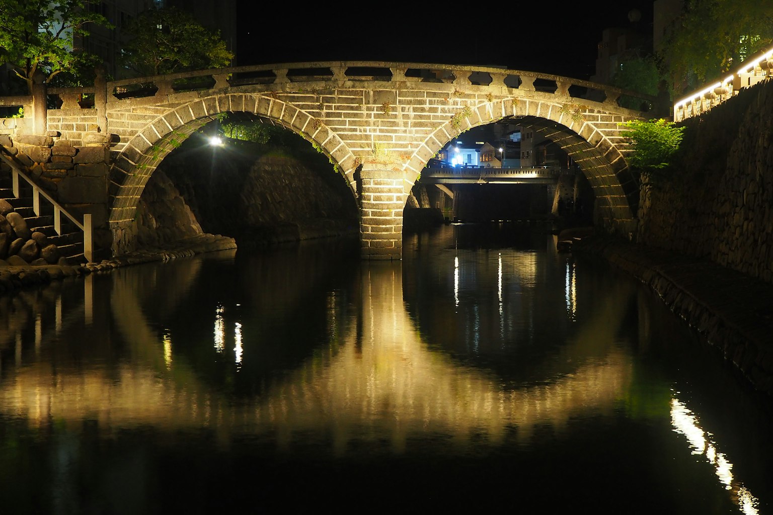 Bellissimo ponte ad arco in pietra che si riflette nell'acqua calma di notte