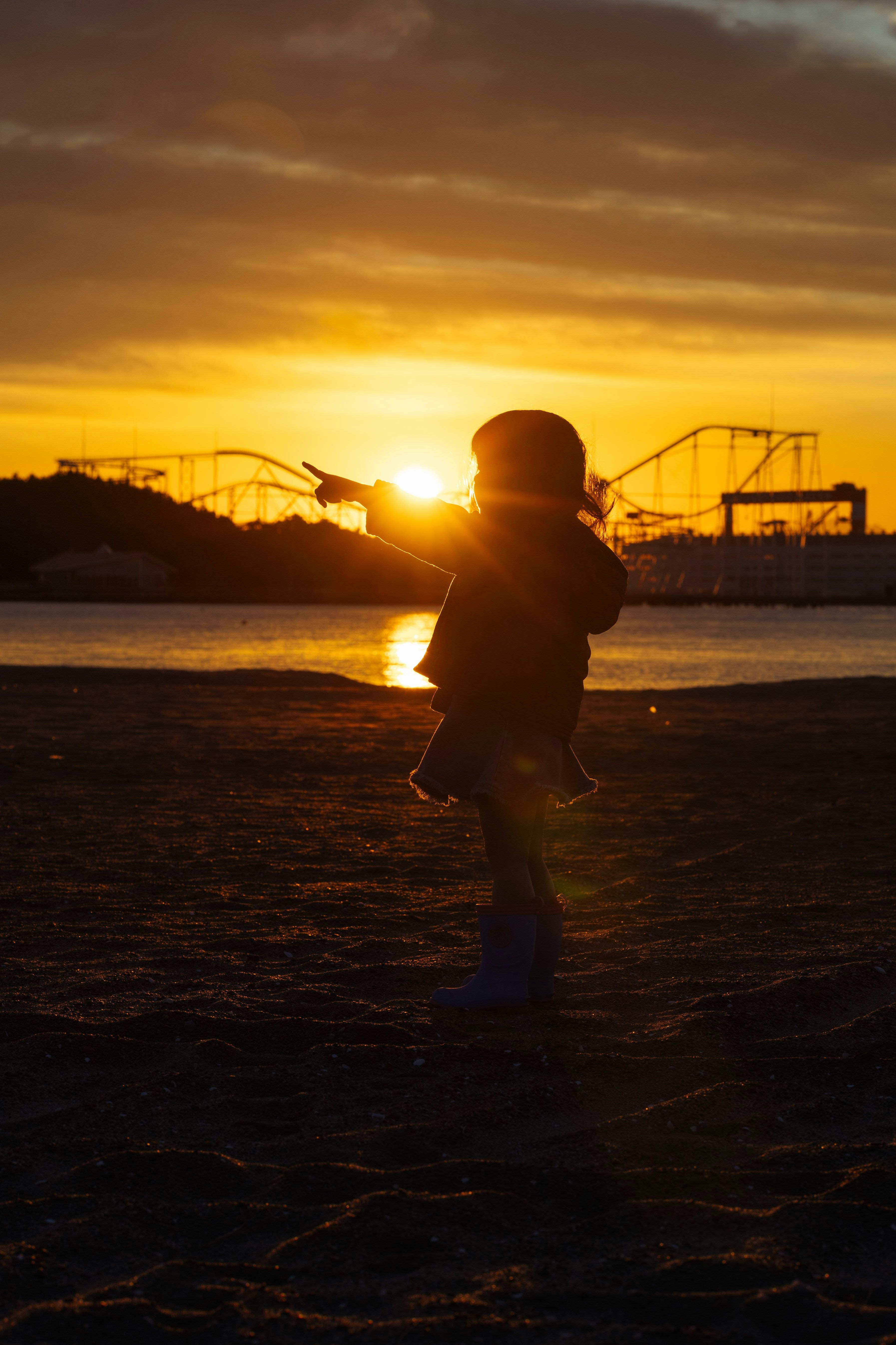 夕日に照らされた海辺で走る子どものシルエット