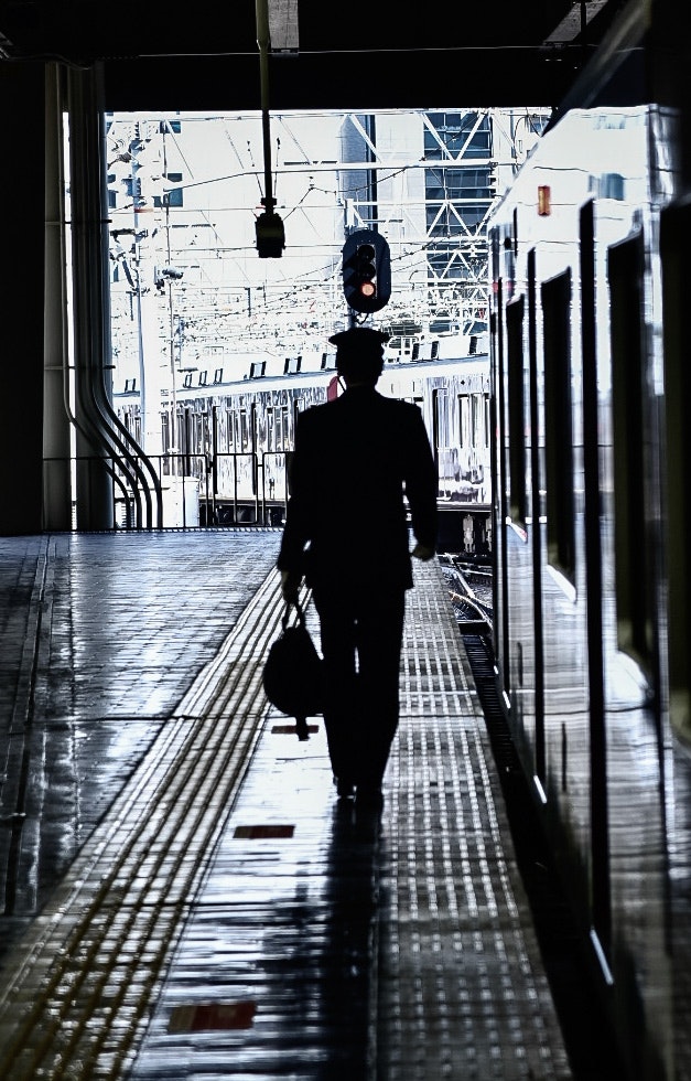 雨上がりの通路を歩くシルエットの人物