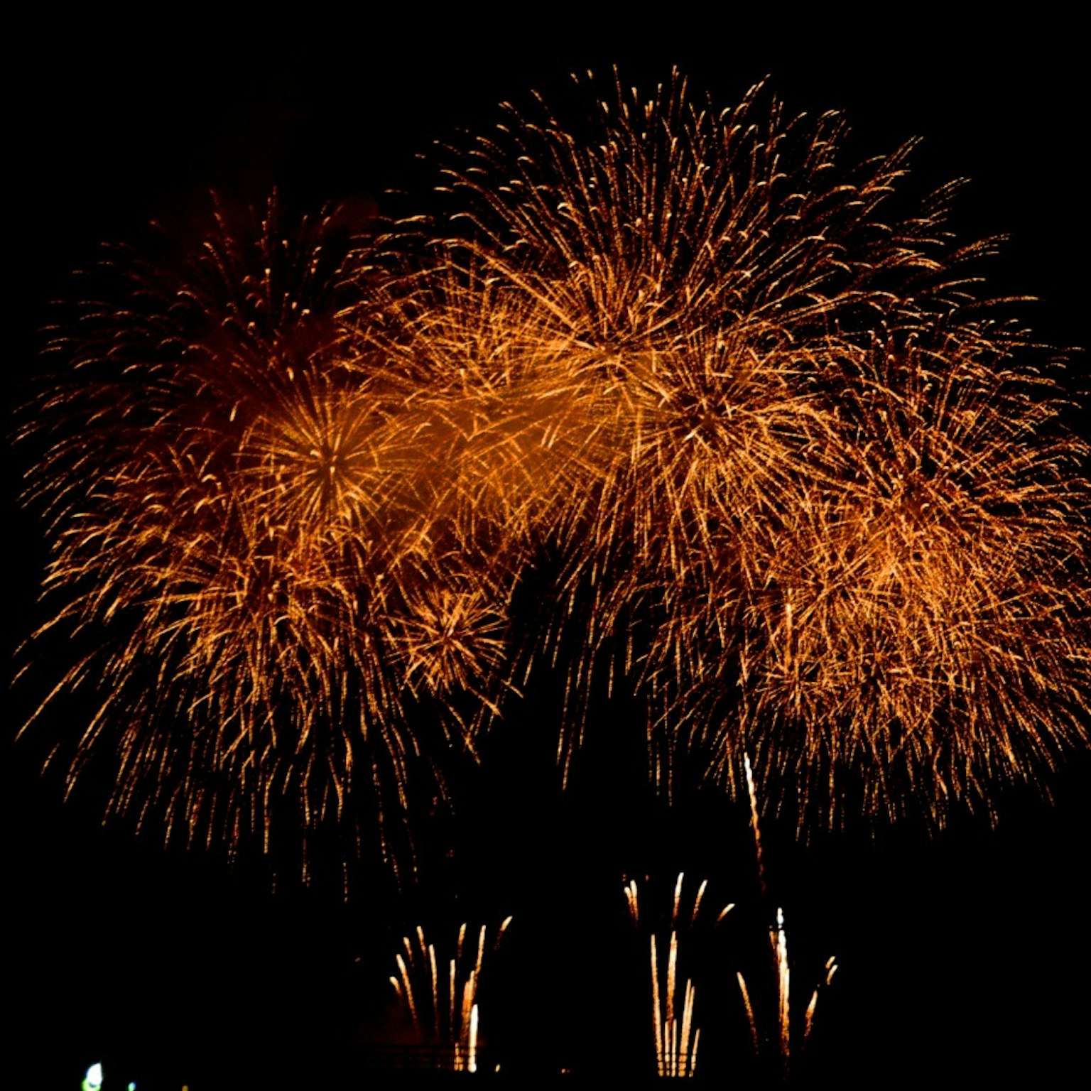 Espectáculo de fuegos artificiales naranjas estallando en el cielo nocturno