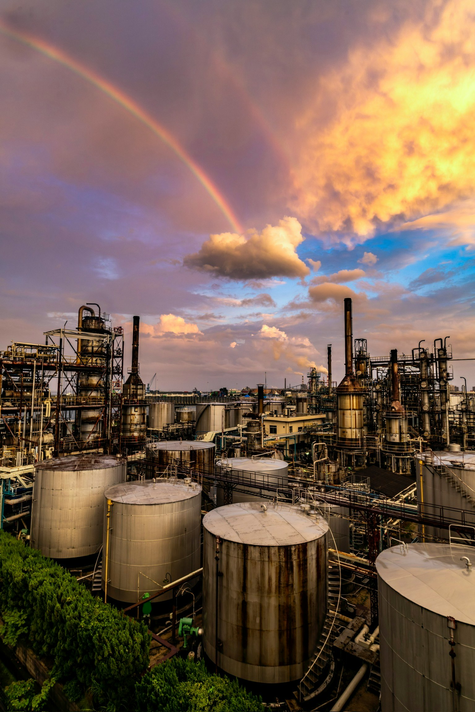 Industrial facility with a rainbow and sunset sky
