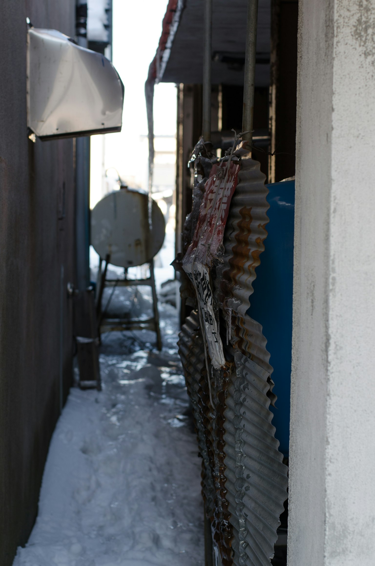 Narrow pathway with snow featuring metallic objects and a blue box