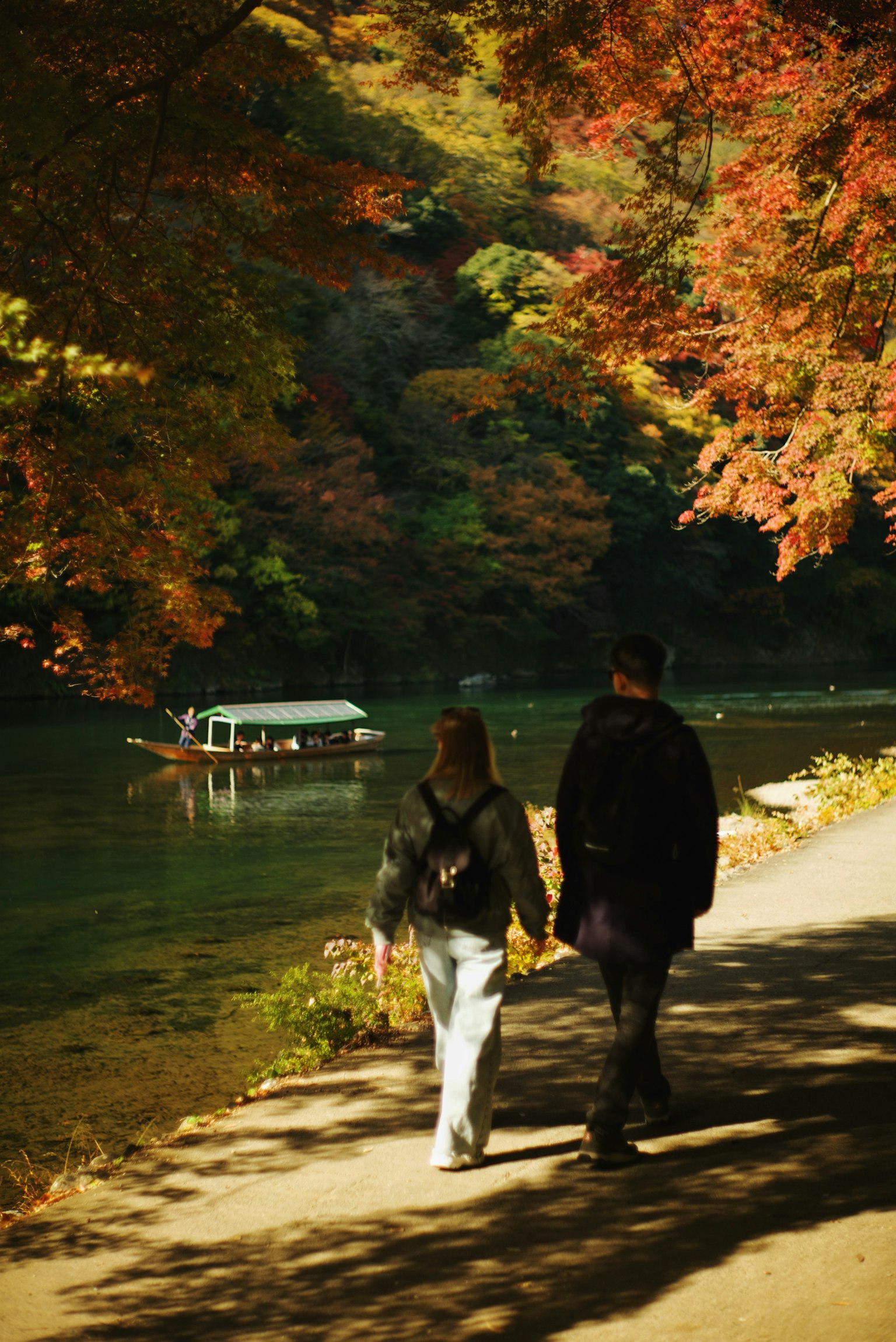 秋の紅葉の中を歩くカップルと静かな川の風景