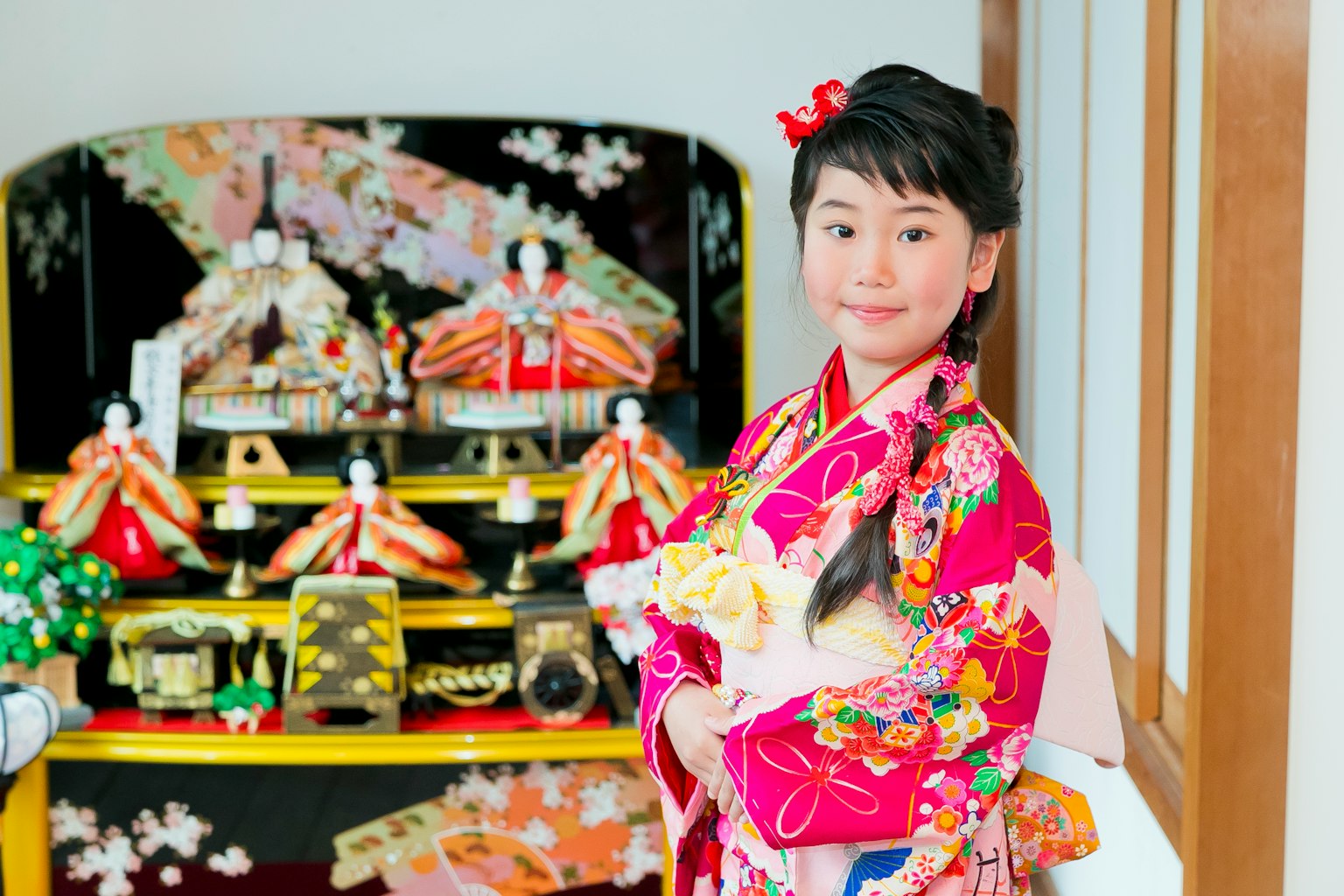 穿着色彩斑斓和服的女孩在玩偶和装饰品前微笑